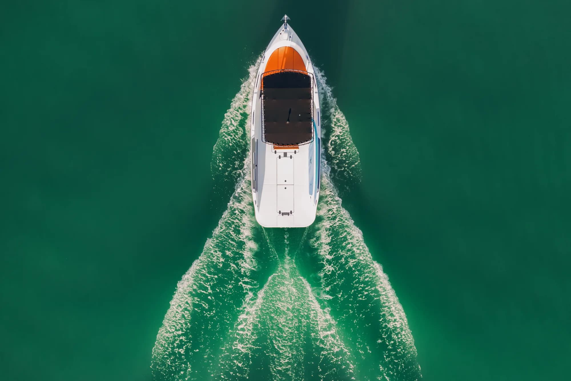 The Wia 230 CC seen from directly above on green water, its open cockpit, orange seating and centre console laid out under the black T-top.