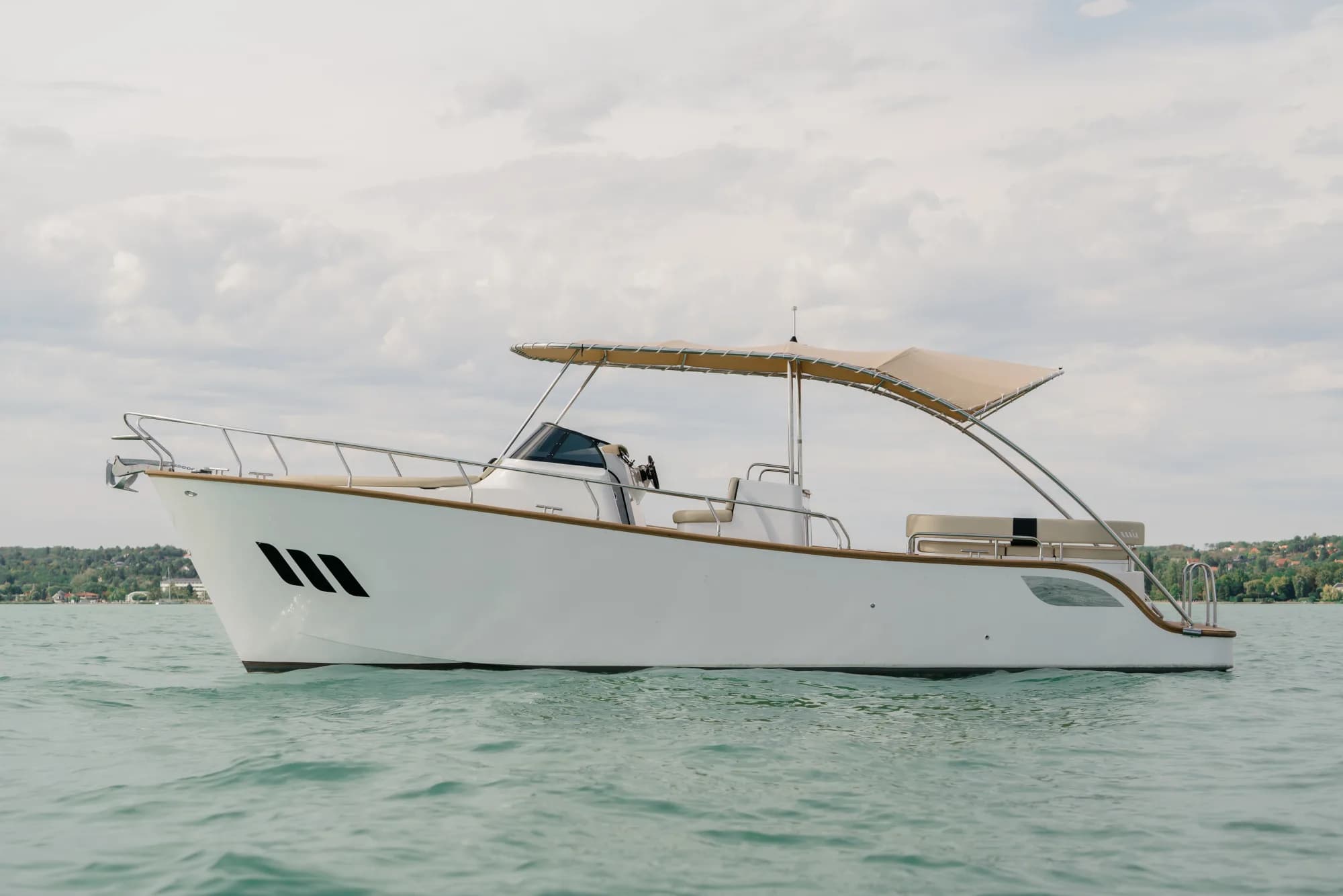 The white-hulled Wia 330 under way, its cream canvas top raised over the open cockpit and tan upholstery, with teak deck trim.