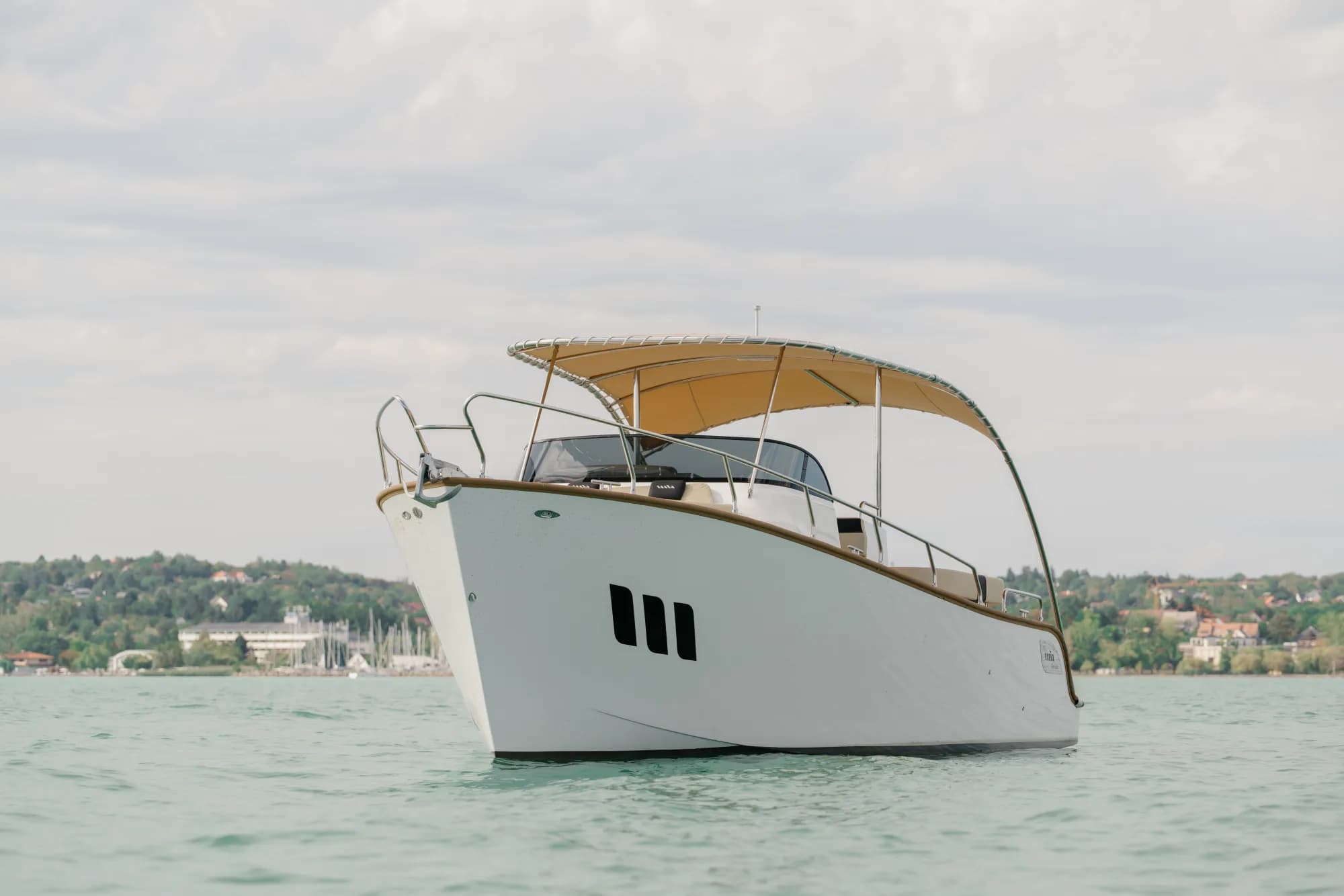 The white-hulled Wia 330 under way, its cream canvas top raised over the open cockpit and tan upholstery, with teak deck trim.