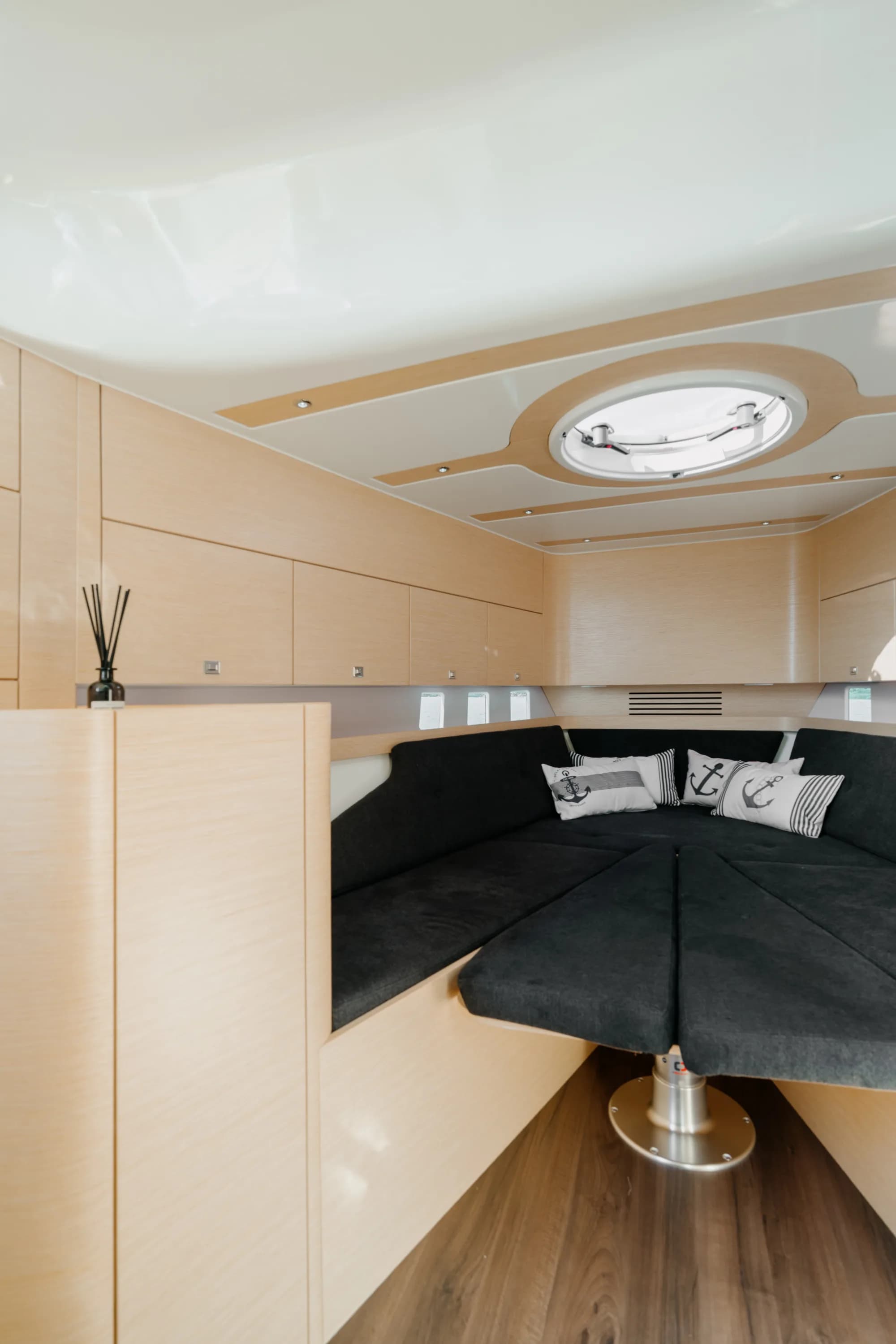 A cabin of the Wia 330 finished in light oak with charcoal upholstery and daylight from an overhead hatch.