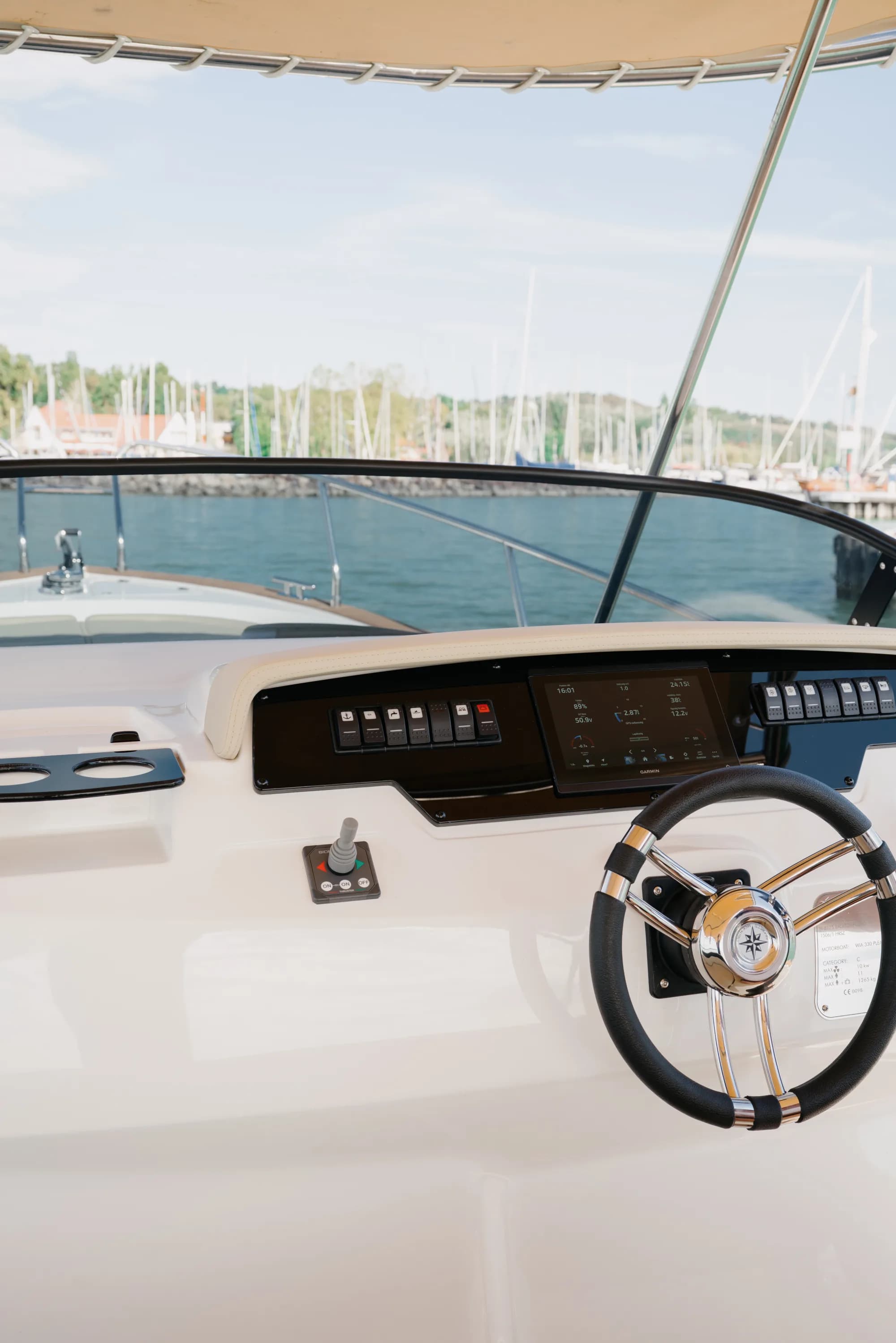 The cockpit of the Wia 330 with tan upholstery, a teak table and the helm under the cream canvas top.