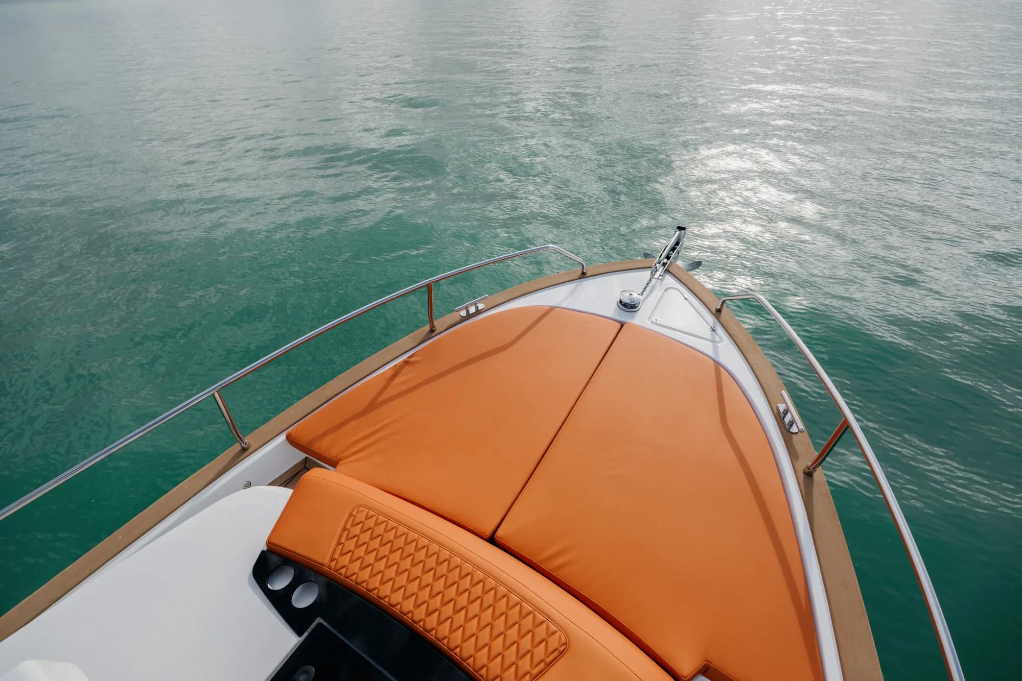 The white-hulled Wia 350 under way, its white hardtop over the enclosed helm and orange cushions in the cockpit.