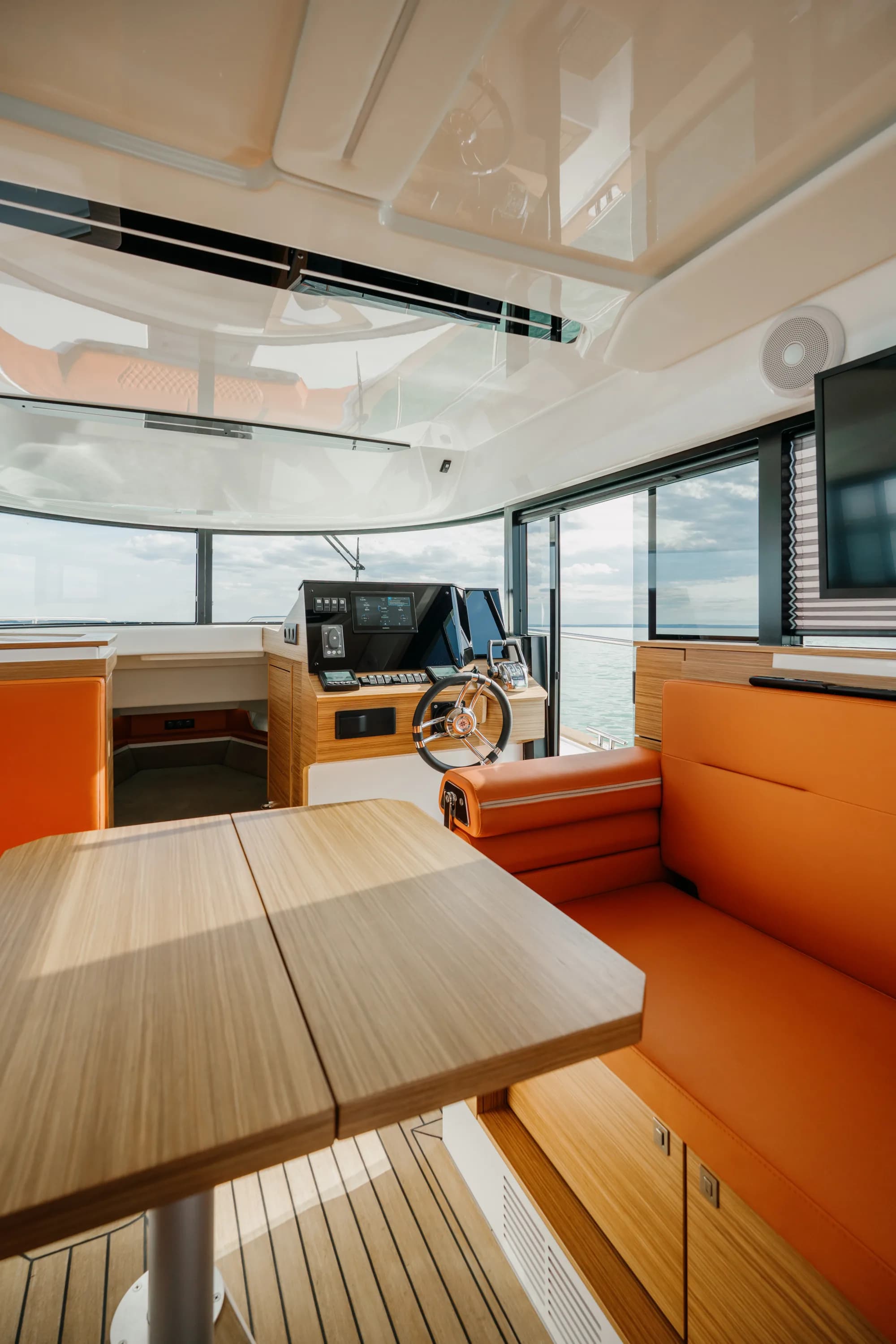 The cockpit of the Wia 350 with orange leather seating, teak decking and the enclosed helm ahead.