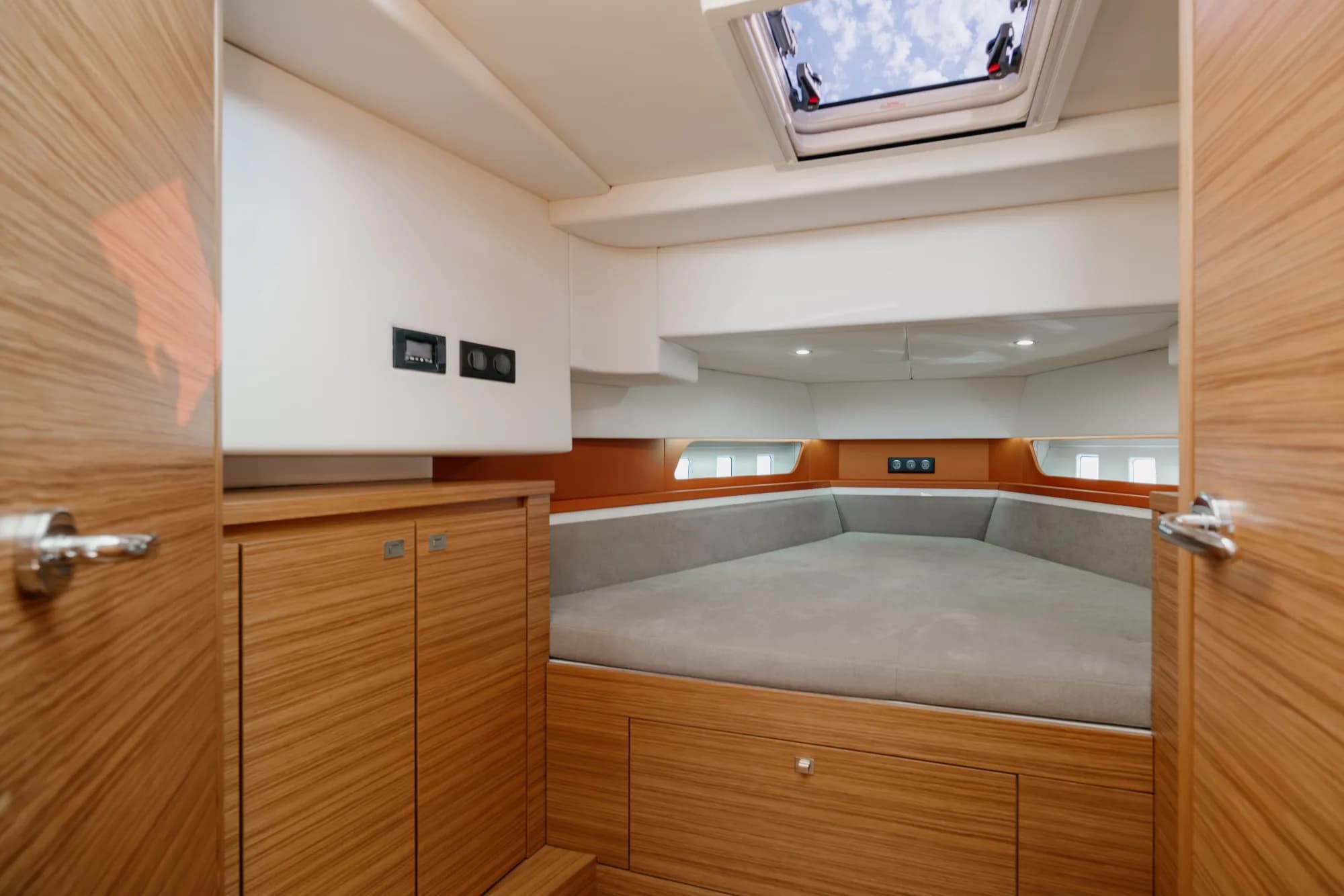 The enclosed wheelhouse of the Wia 350: bright orange leather seating, a light oak dinette, a chrome-spoked helm and a touchscreen at the console, wrapped in panoramic windows.