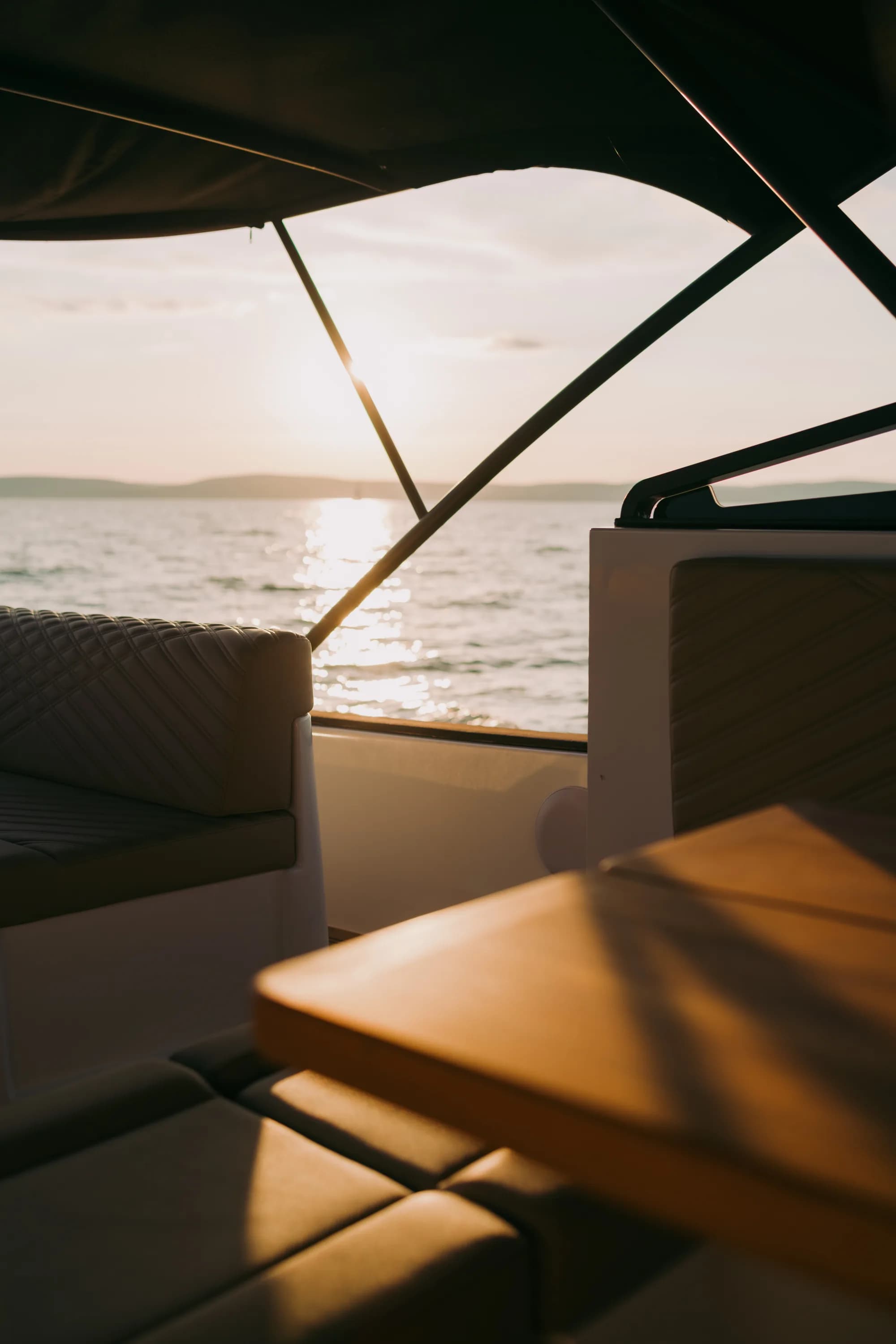 The white-hulled Wia 450 Cabrio under way on the water at dusk, its black canvas top raised over the open cockpit.
