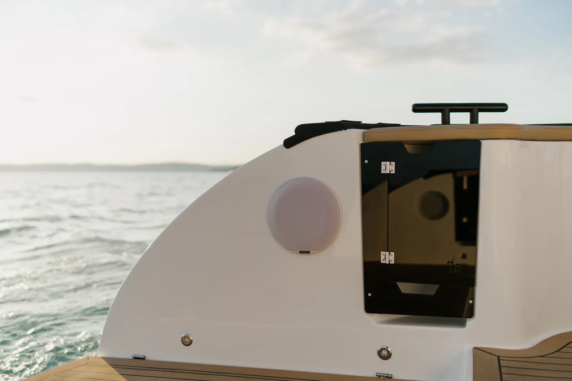 The white-hulled Wia 450 Cabrio under way on the water at dusk, its black canvas top raised over the open cockpit.