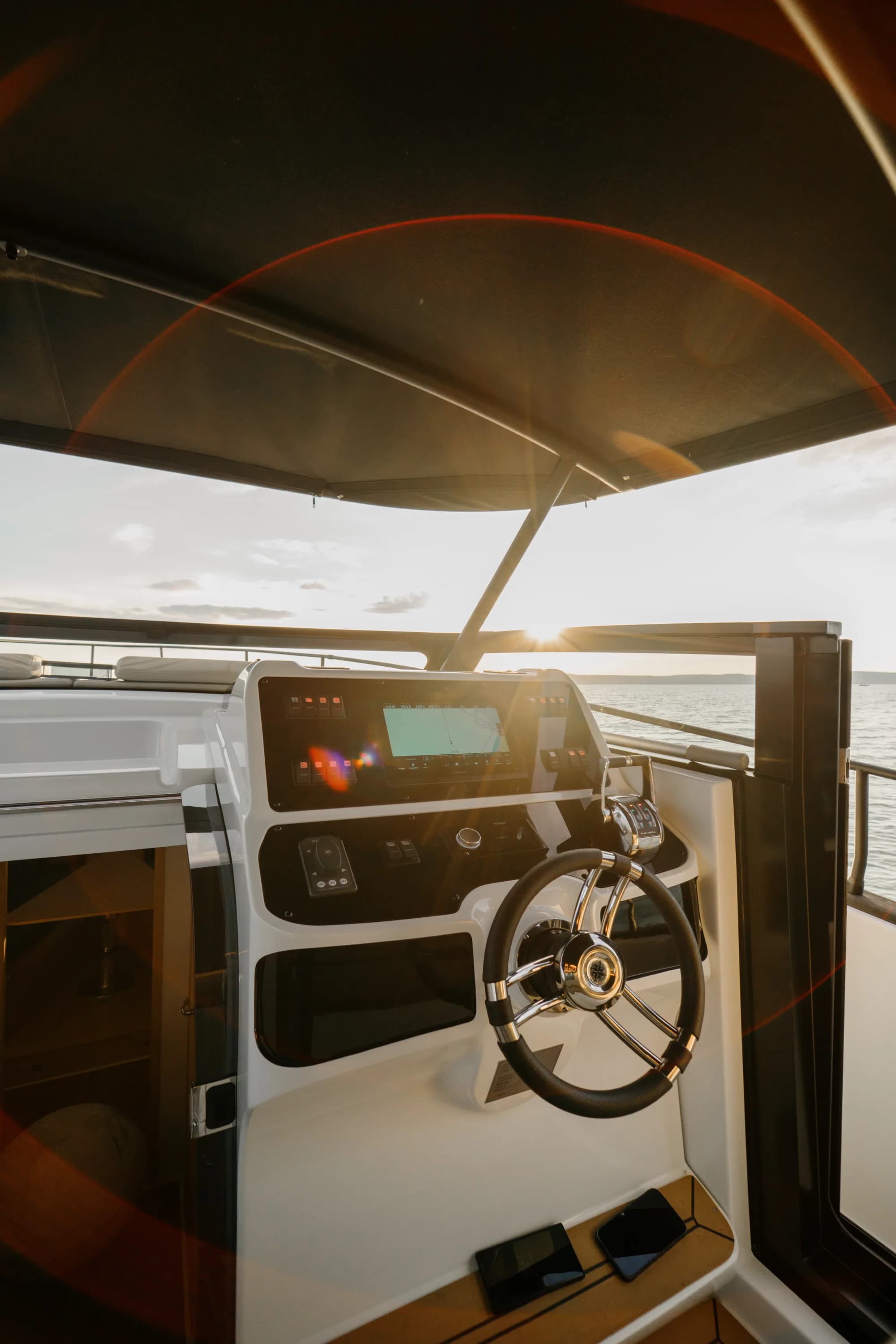 The white-hulled Wia 450 Cabrio under way on the water at dusk, its black canvas top raised over the open cockpit.