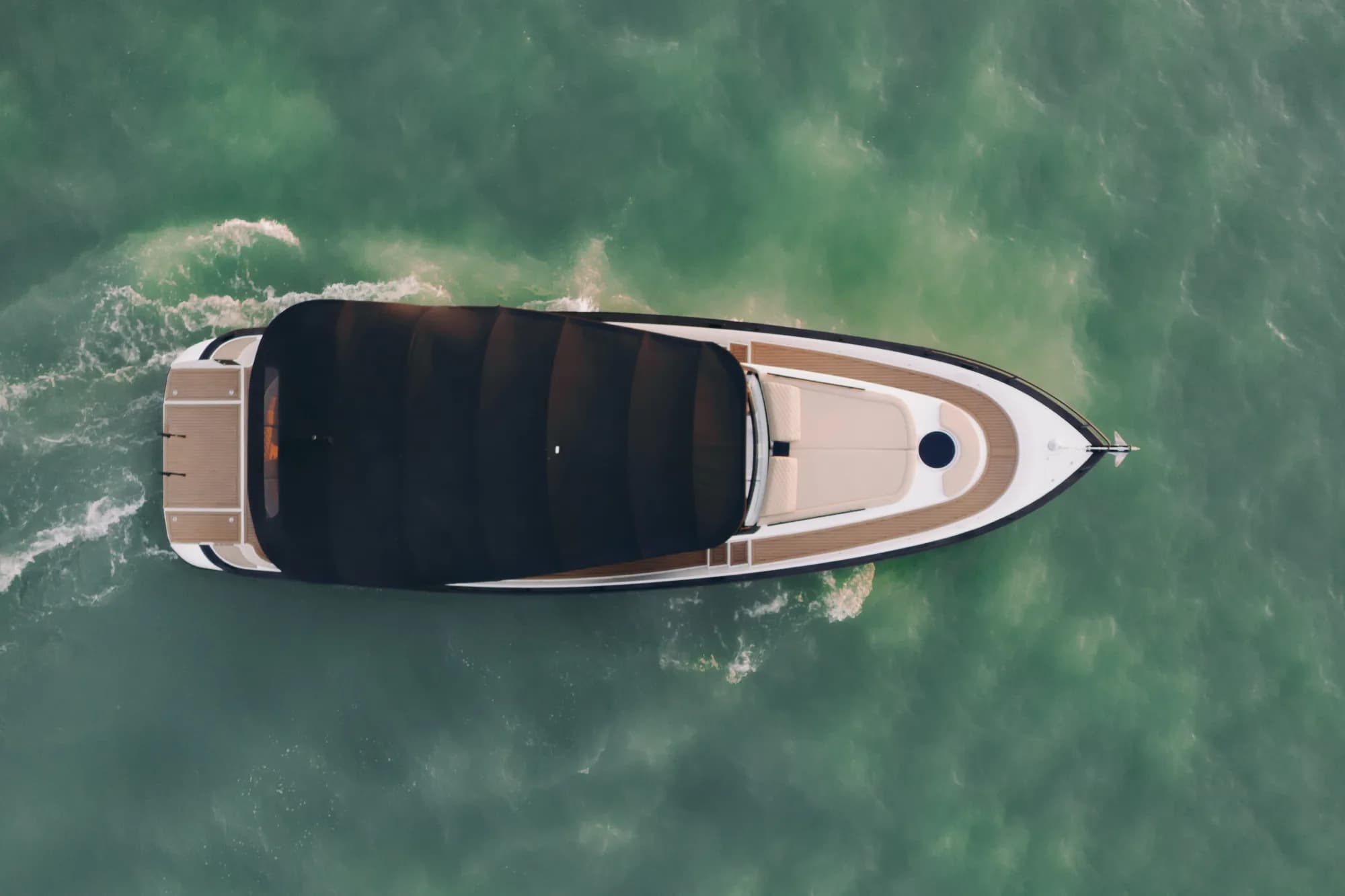 The white-hulled Wia 450 Cabrio under way on the water at dusk, its black canvas top raised over the open cockpit.