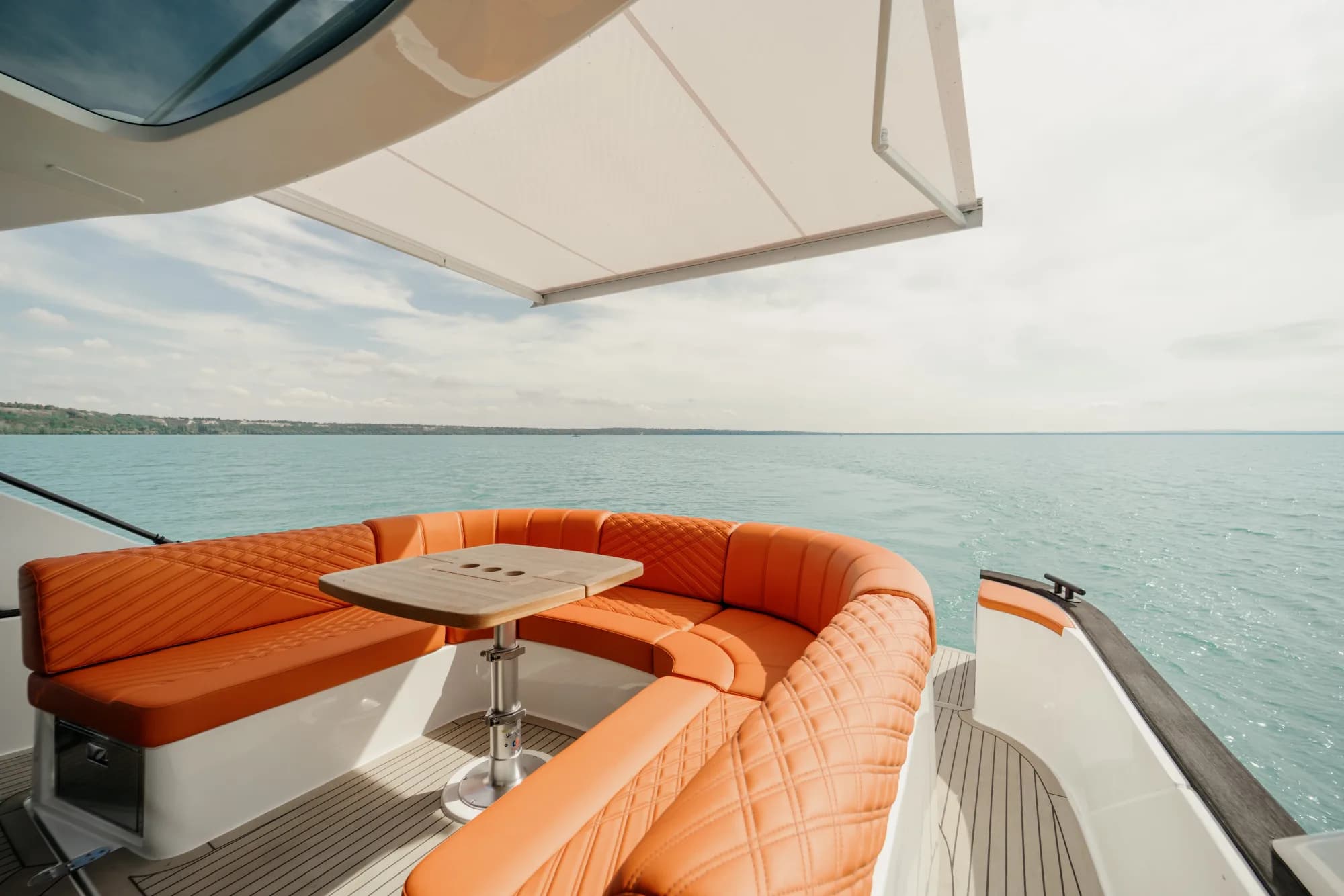 The dark-grey-hulled Wia 450 HardTop under way, its white hardtop over the enclosed helm and orange sunpads on the foredeck.