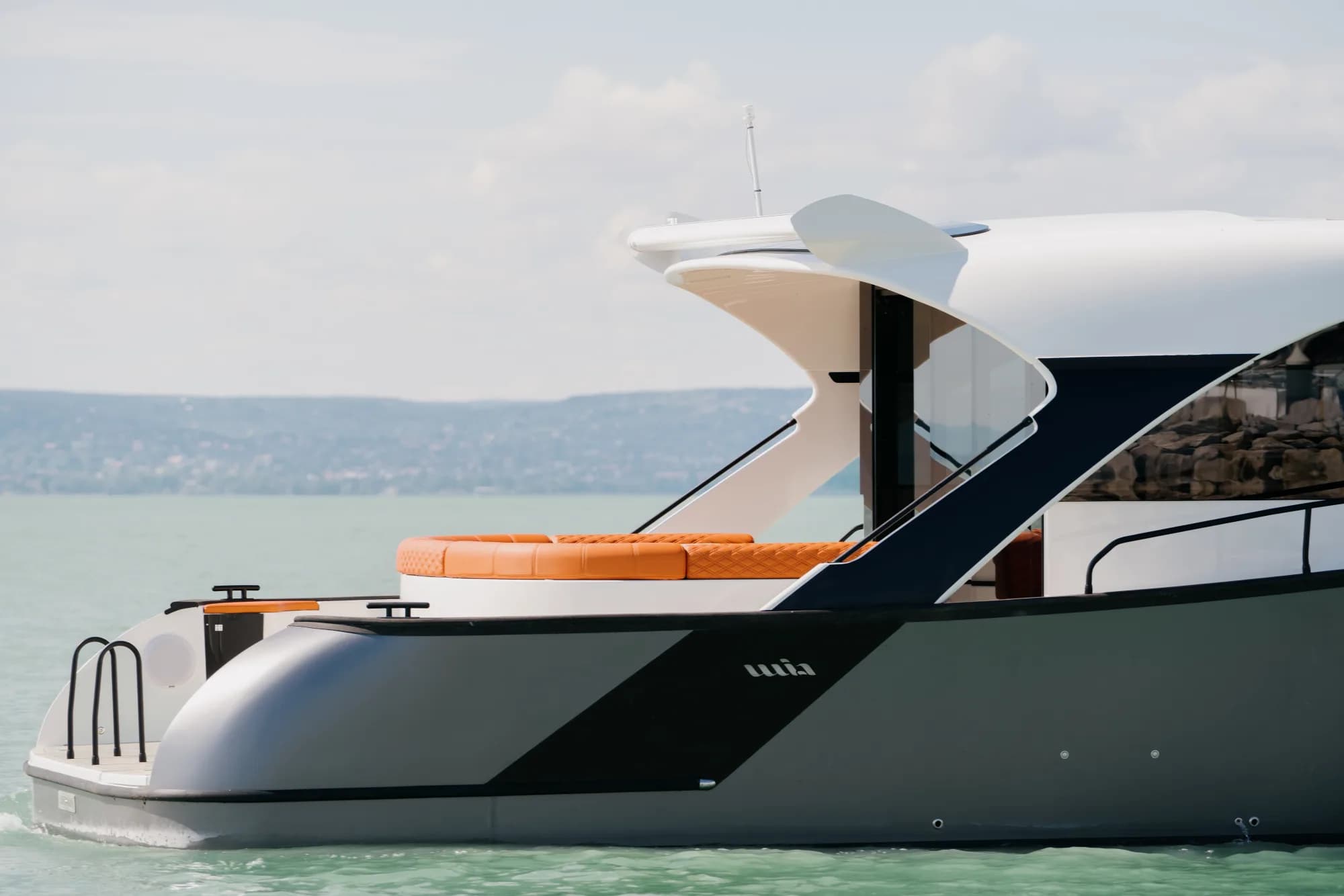 The dark-grey-hulled Wia 450 HardTop under way, its white hardtop over the enclosed helm and orange sunpads on the foredeck.