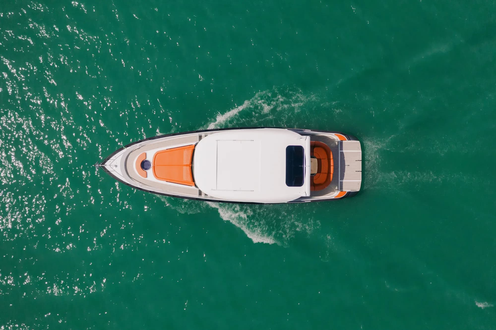 The dark-grey-hulled Wia 450 HardTop under way, its white hardtop over the enclosed helm and orange sunpads on the foredeck.