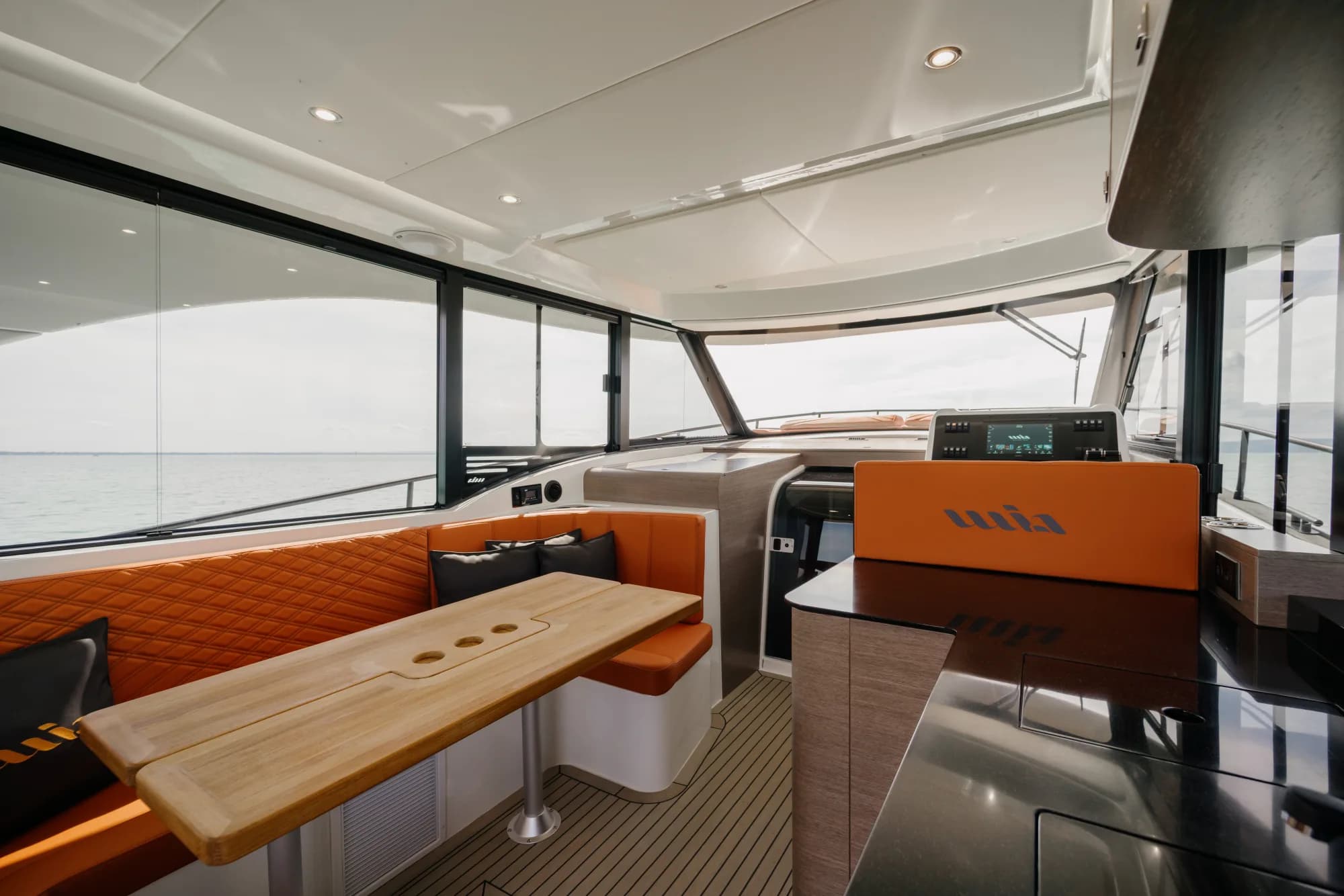 The cockpit of the Wia 450 HardTop with orange leather seating and teak decking beneath the white hardtop.