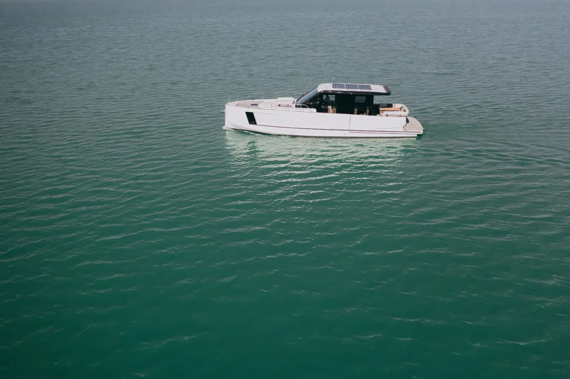 The white-hulled Wia 520 HardTop under way, its dark hardtop with roof solar panels over the enclosed saloon and teak decks.