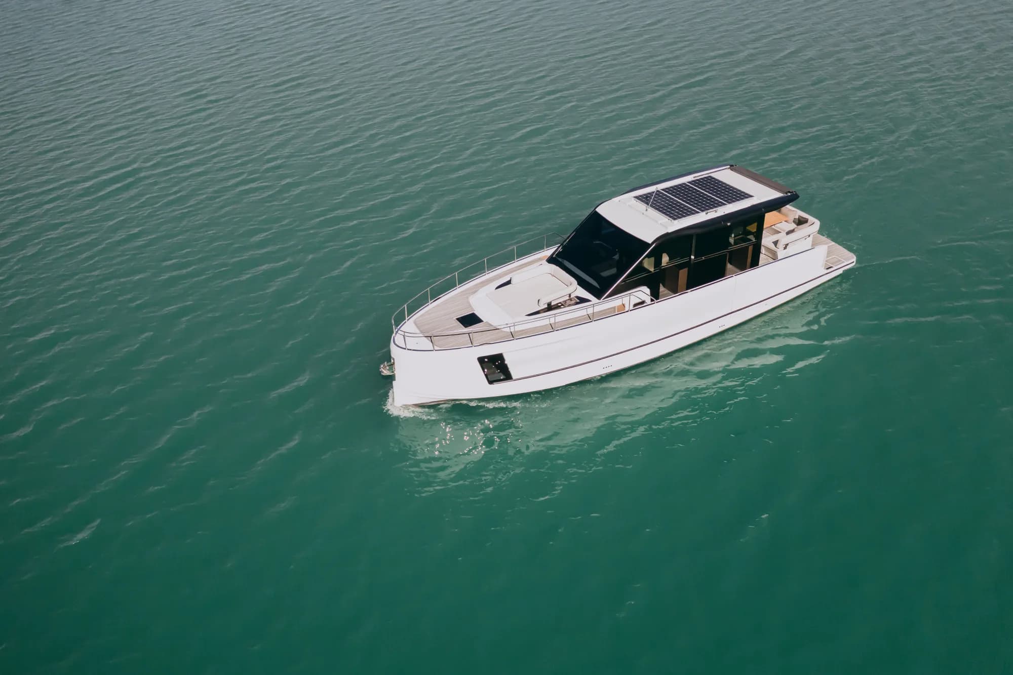 The white-hulled Wia 520 HardTop under way, its dark hardtop with roof solar panels over the enclosed saloon and teak decks.