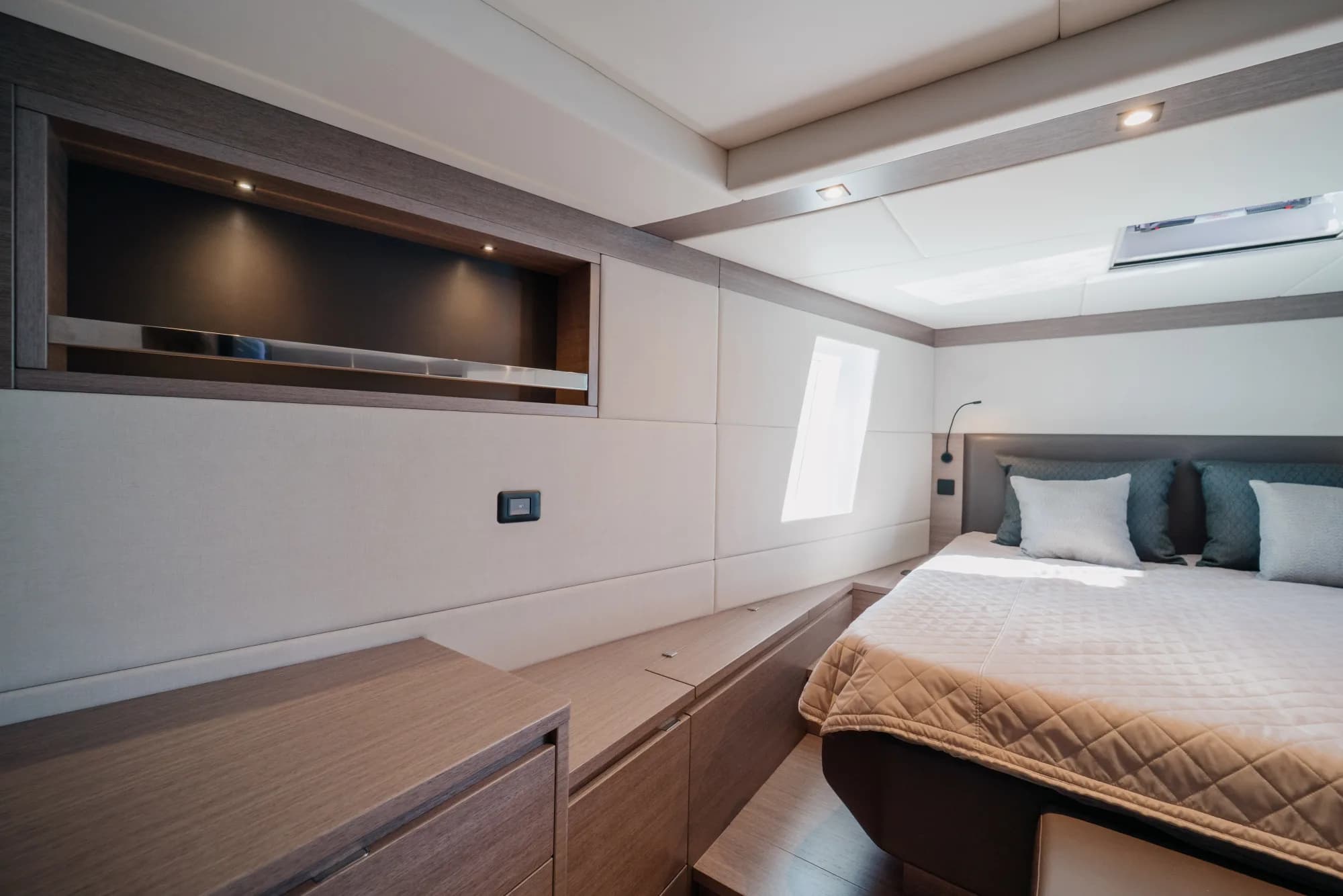The enclosed saloon of the Wia 520 HardTop: a cream L-shaped sofa, light oak panelling, a galley with a dark worktop, a teak sole and the helm ahead, wrapped in panoramic windows.