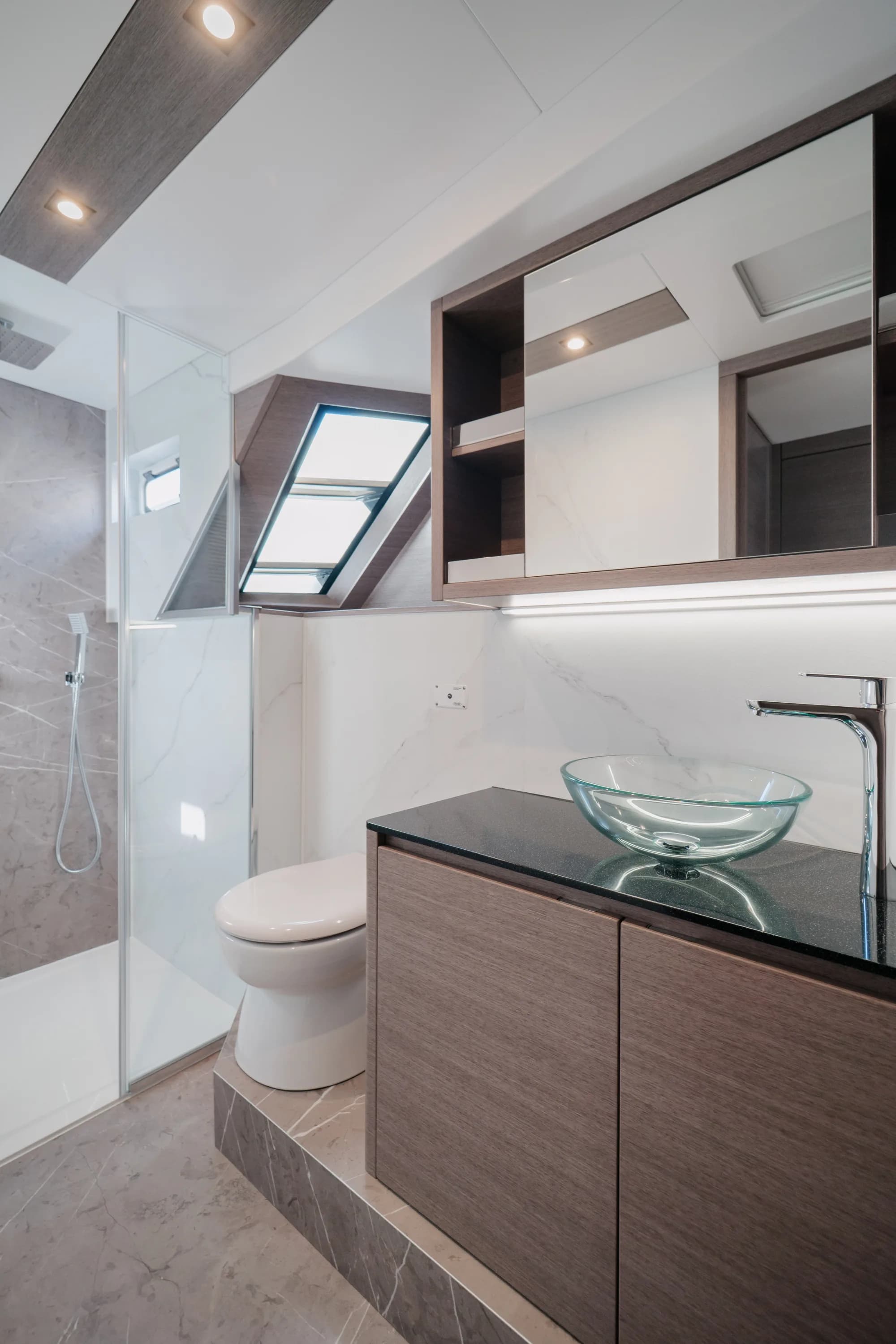 The enclosed saloon of the Wia 520 HardTop: a cream L-shaped sofa, light oak panelling, a galley with a dark worktop, a teak sole and the helm ahead, wrapped in panoramic windows.