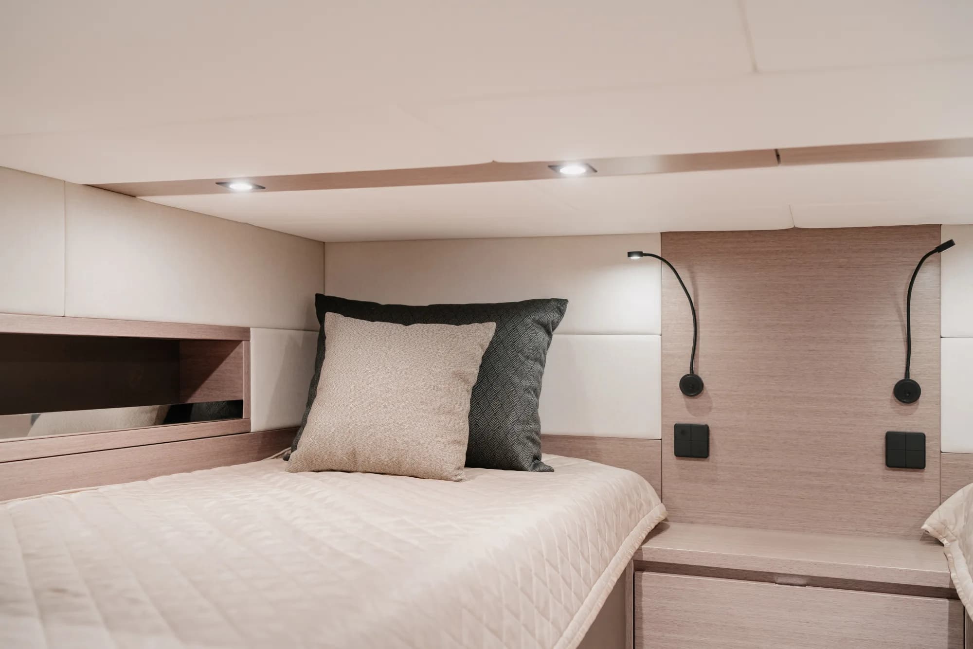 The enclosed saloon of the Wia 520 HardTop: a cream L-shaped sofa, light oak panelling, a galley with a dark worktop, a teak sole and the helm ahead, wrapped in panoramic windows.
