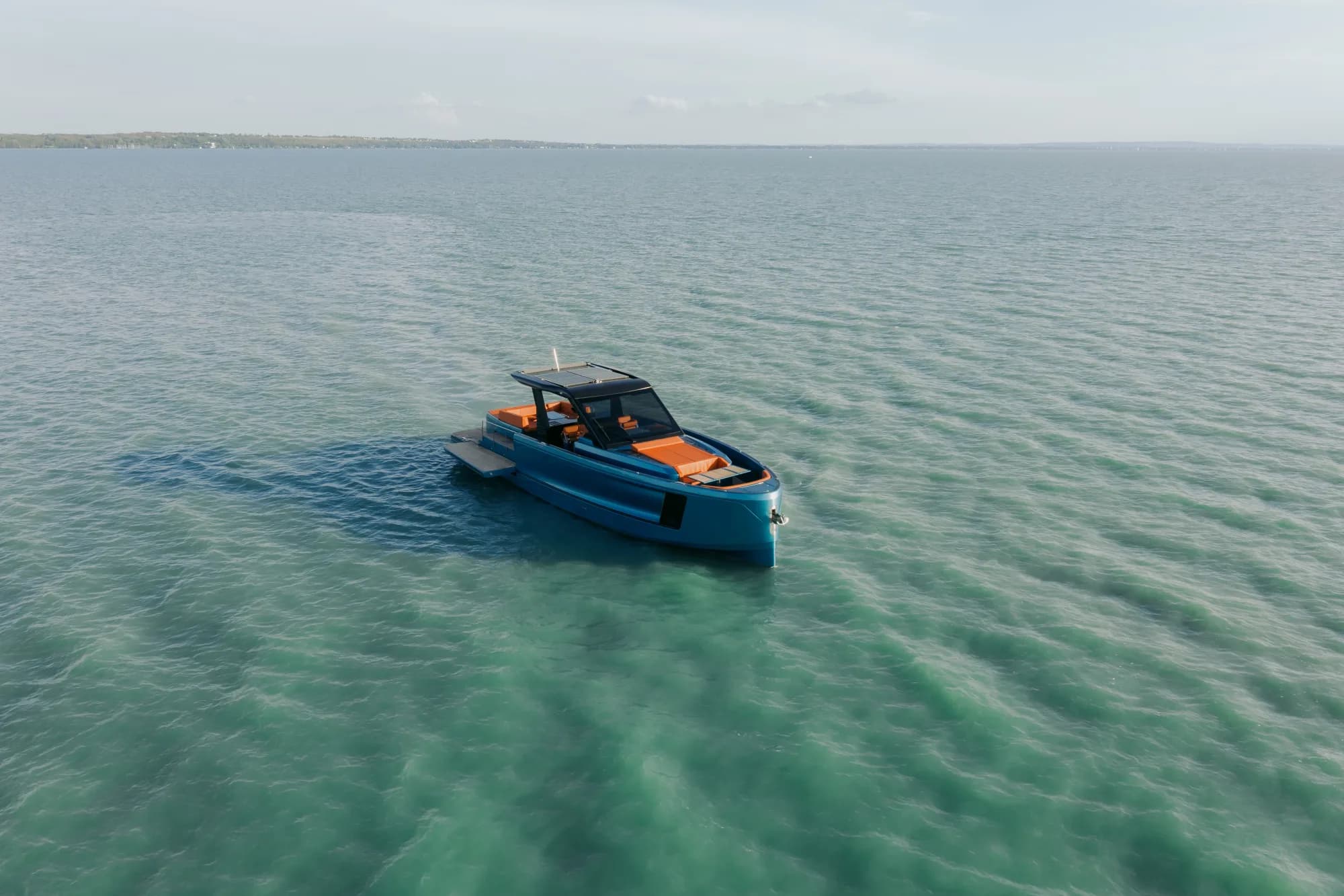 The Wia 520 Open cruising on Lake Balaton, its blue hull and open cockpit with orange sunpads seen from the water.
