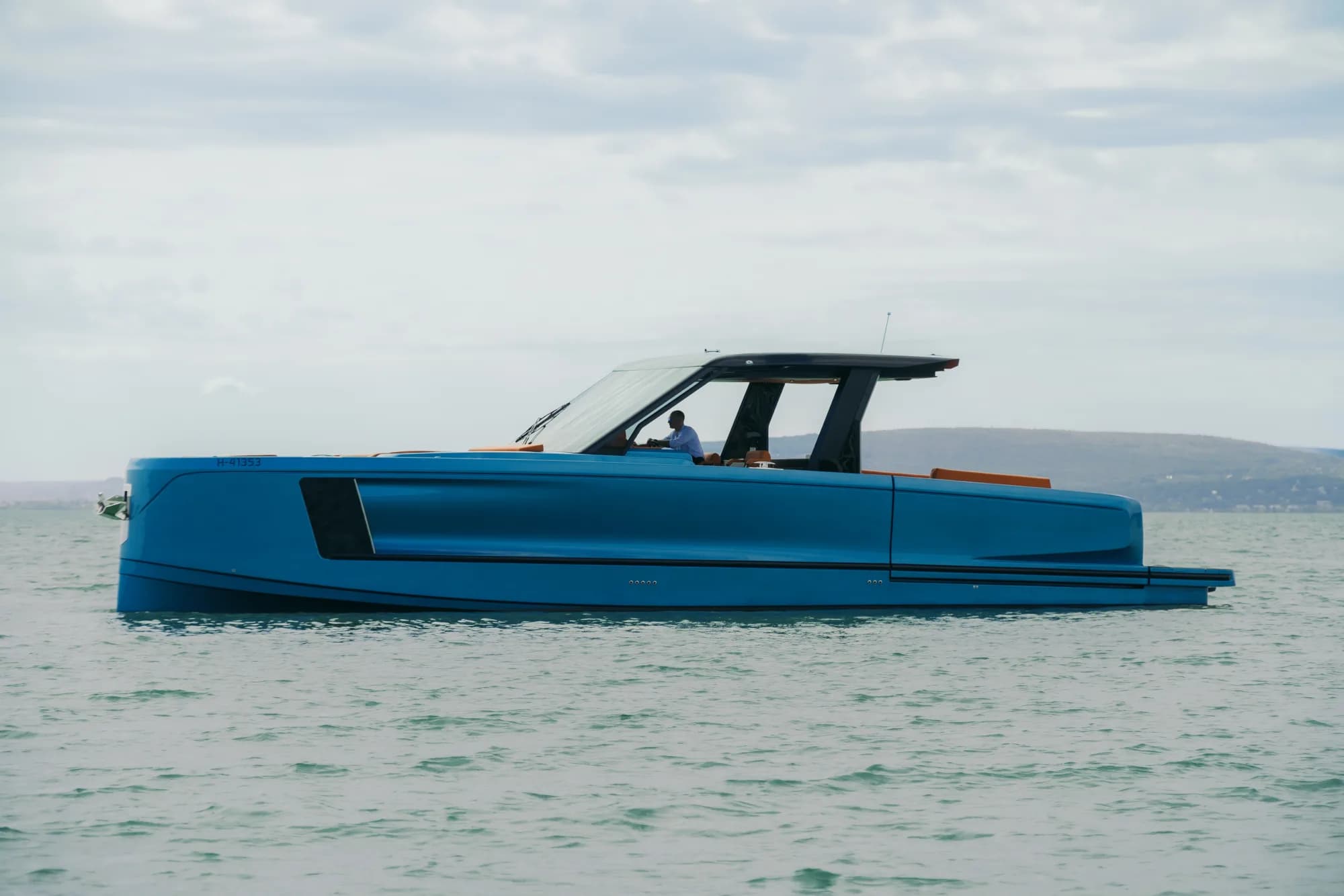 The blue-hulled Wia 520 Open at speed, a clean wake trailing behind its teak-trimmed transom.