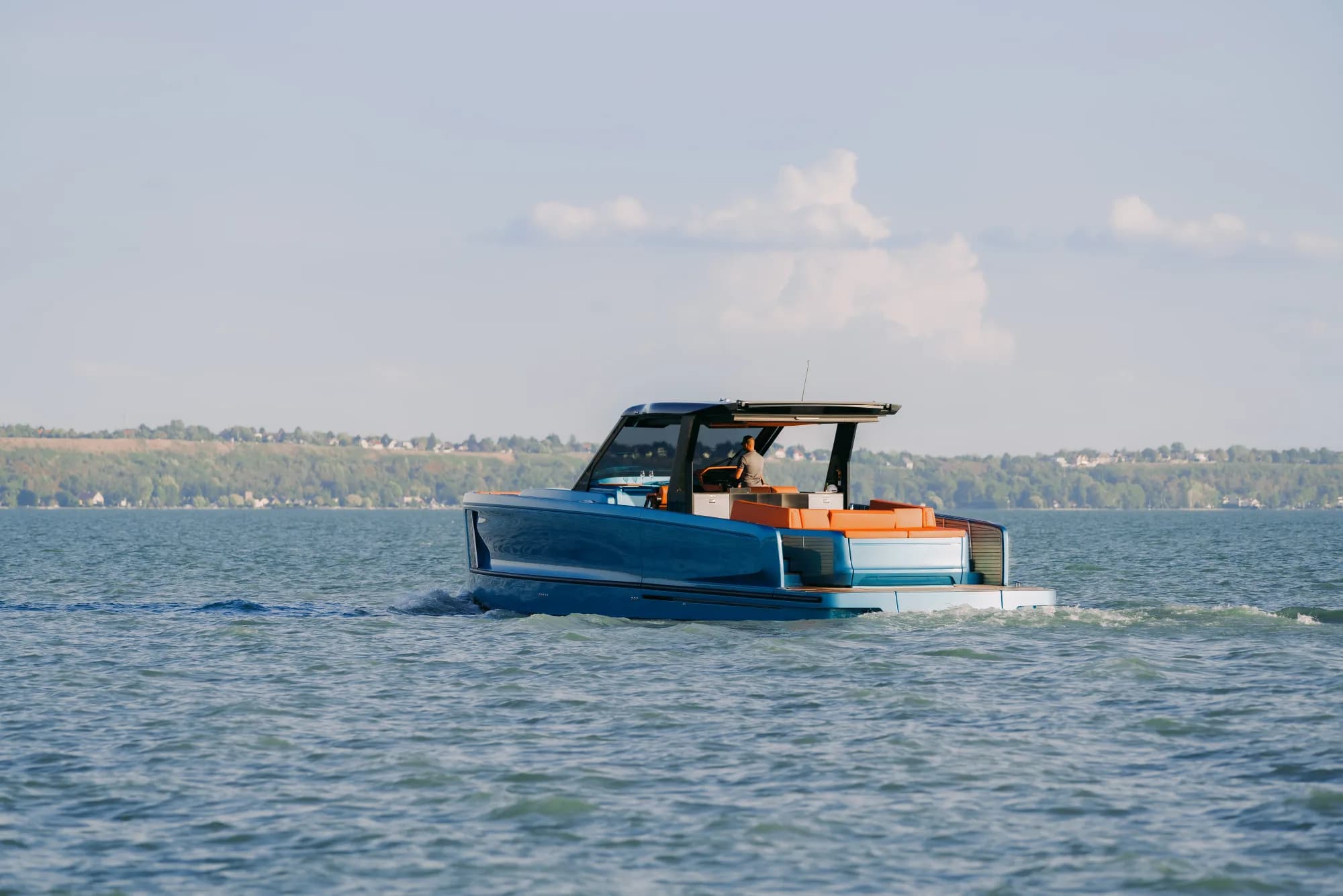 The Wia 520 Open on Lake Balaton seen from the water, its teak side decks and orange cockpit seating in view.