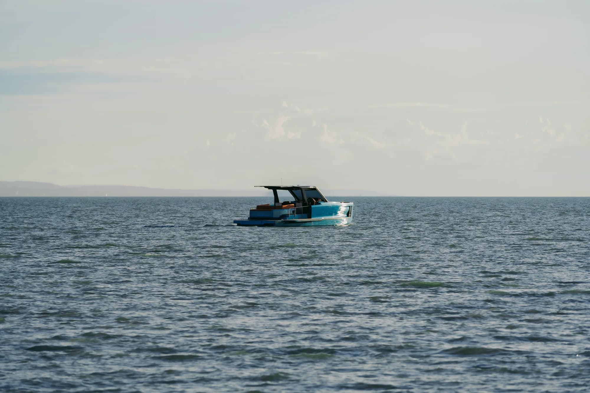 The Wia 520 Open in silhouette on the shimmering backlit water of Lake Balaton, hills on the horizon.