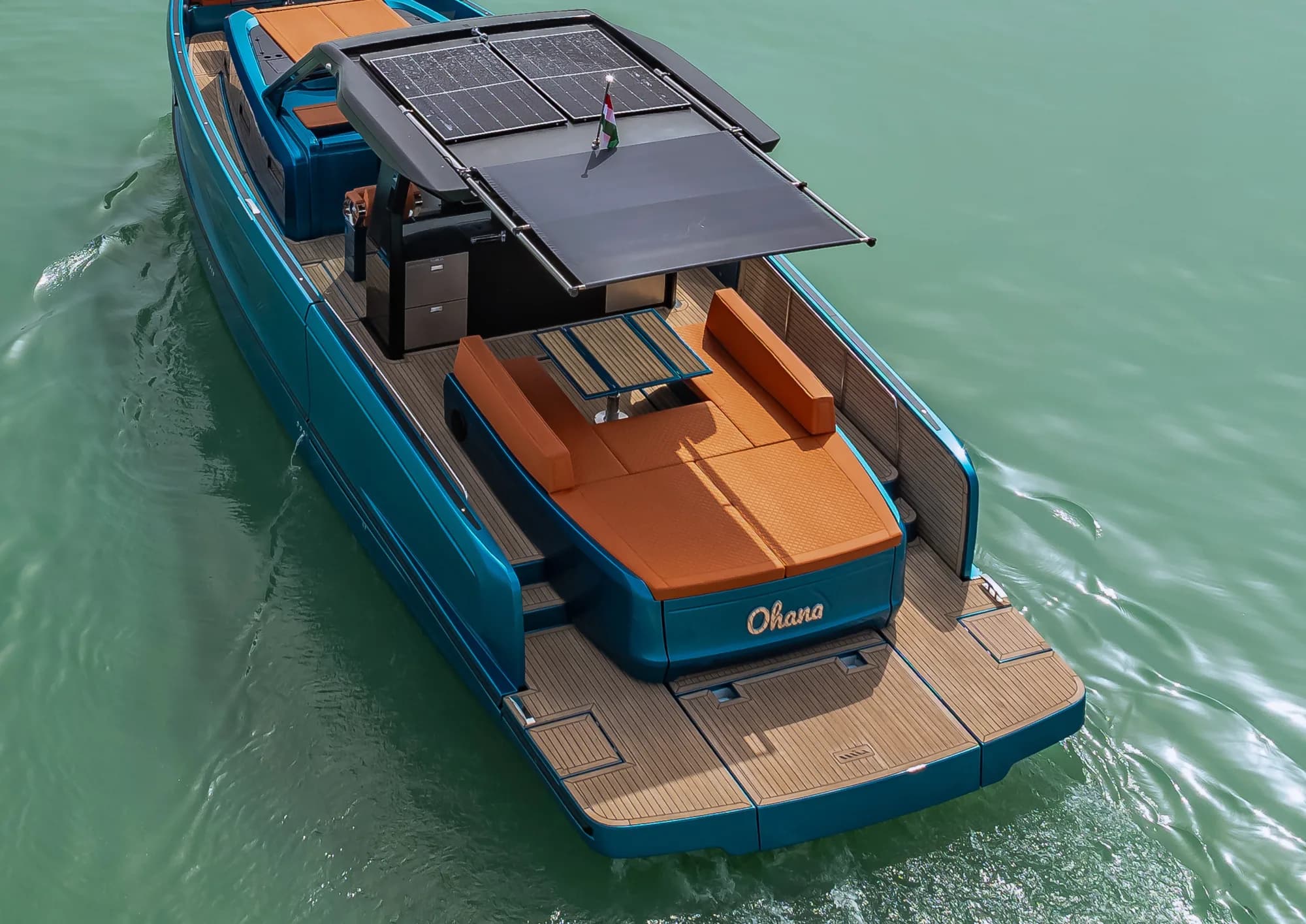 The aft deck of the Wia 520 Open under its motorised sunshade, orange sunpads and teak decking in the shade.