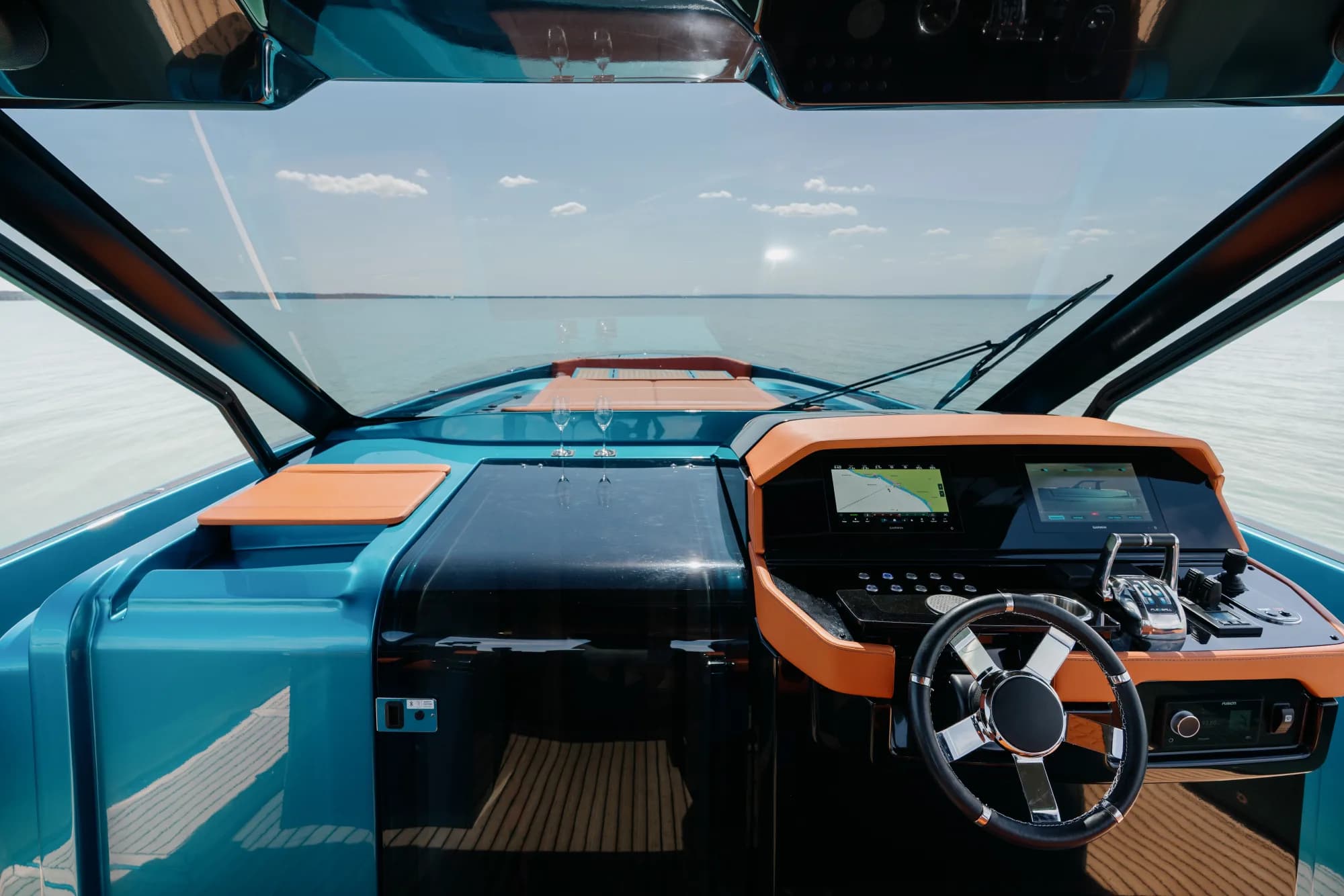 The Wia 520 Open on the water with its sunshade out and orange cockpit seating, the blue hull gleaming.