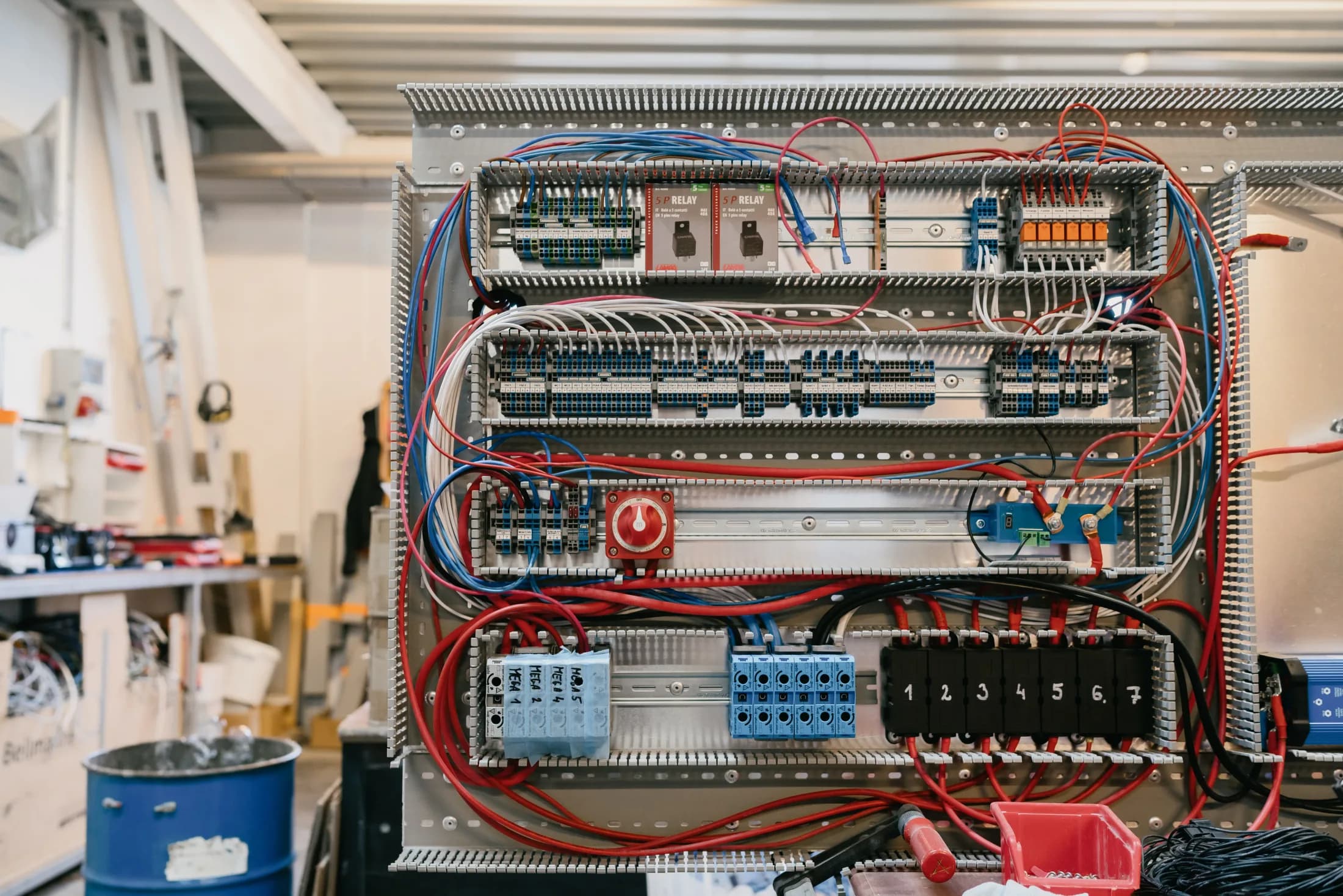 Un tableau électrique marin entièrement câblé, avec relais, borniers et câblage rouge et bleu.