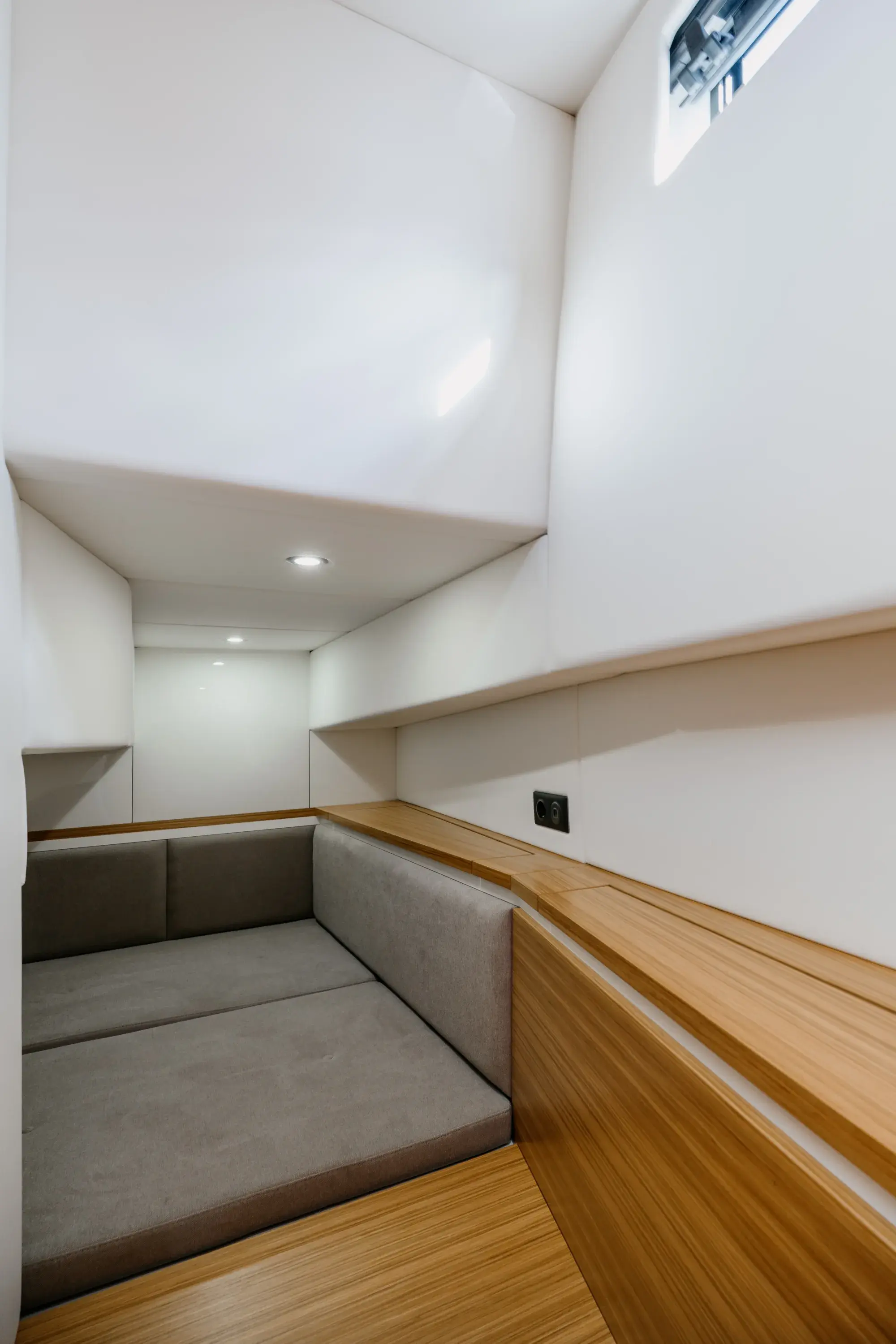 Das geschlossene Steuerhaus des Wia 350: leuchtend orangefarbene Ledersitze, eine Sitzgruppe aus heller Eiche, ein Steuerrad mit Chromspeichen und ein Touchscreen am Pult, umgeben von Panoramafenstern.