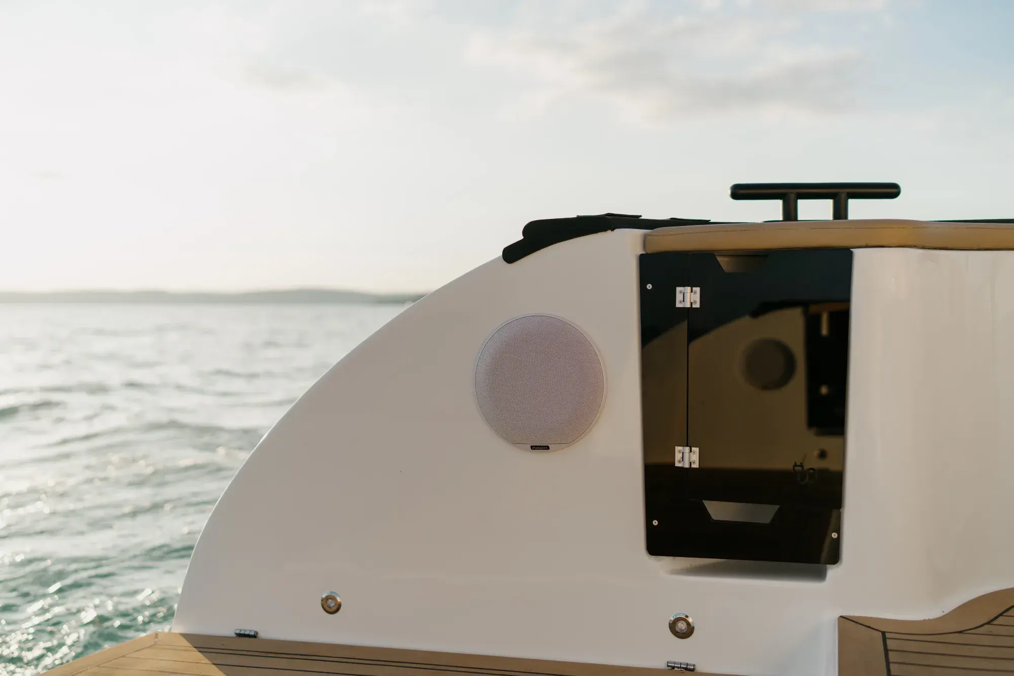 Die Wia 450 Cabrio mit weißem Rumpf in Fahrt auf dem Wasser bei Dämmerung, das schwarze Stoffverdeck über dem offenen Cockpit aufgespannt.