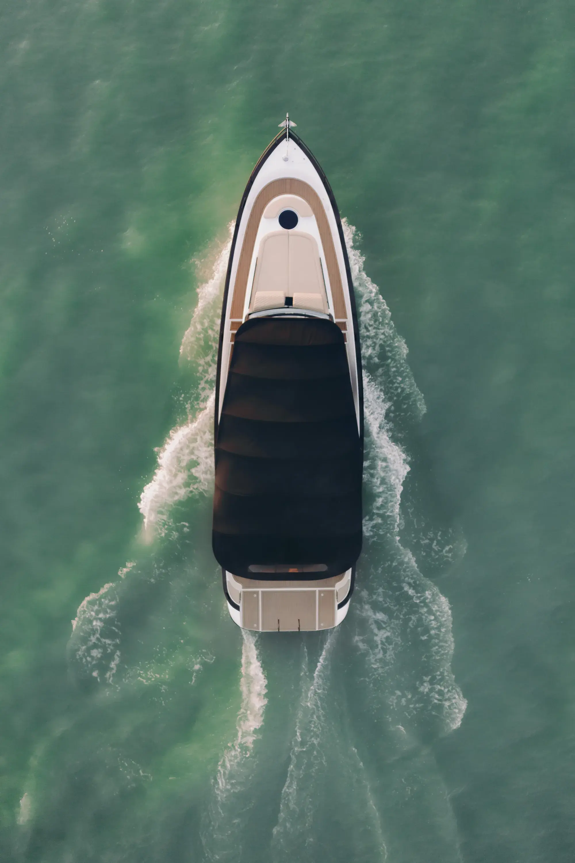 Die Wia 450 Cabrio senkrecht von oben auf grünem Wasser, offenes Cockpit und cremefarbene Sonnenliegen unter dem zurückgefahrenen Verdeck.