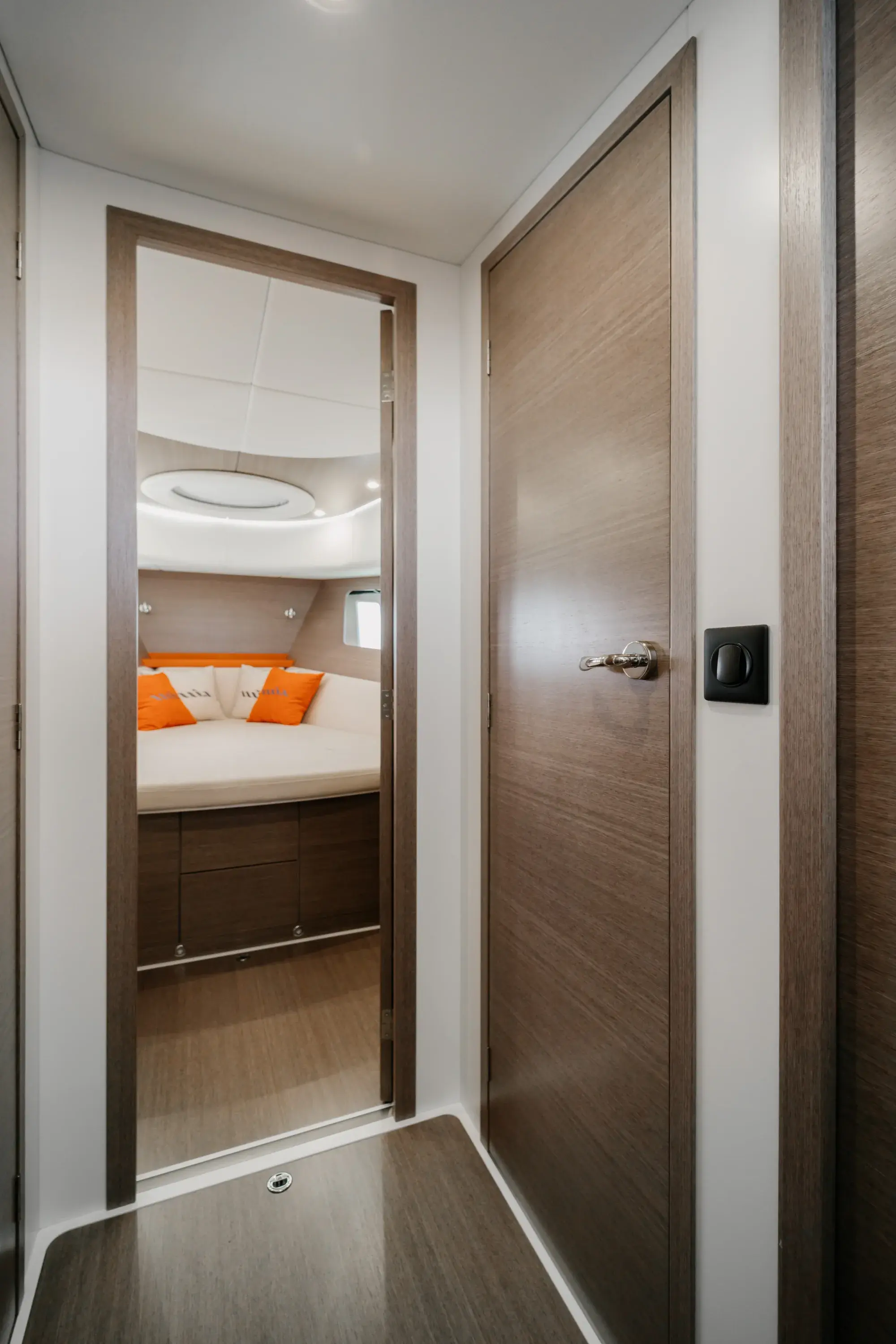 Une cabine de la Wia 450 HardTop en chêne clair, avec touches orange et lumière naturelle des hublots de coque.