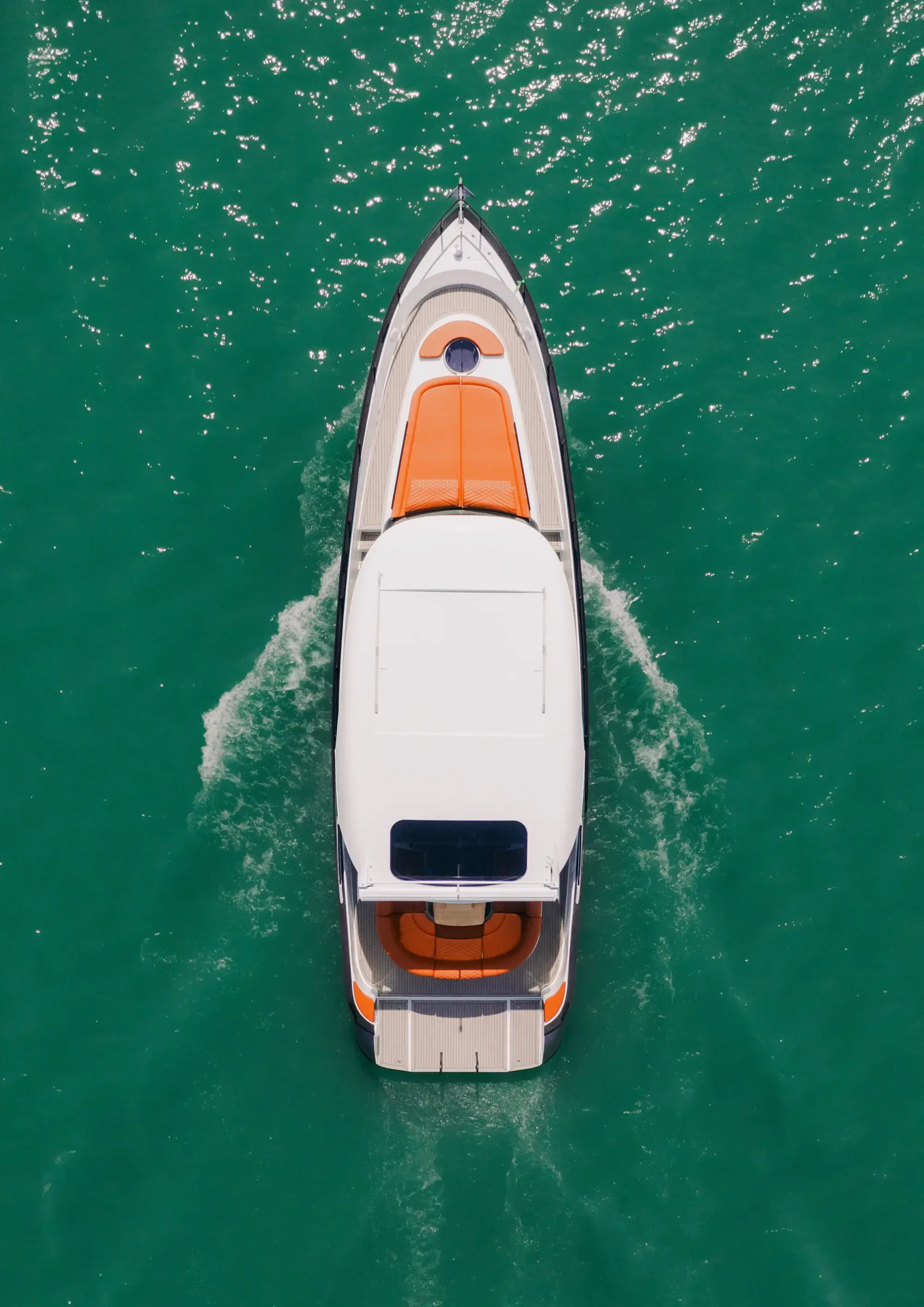 La Wia 450 HardTop vue du dessus, son hardtop blanc, ses passavants en teck et ses bains de soleil de proue orange sur l'eau verte.