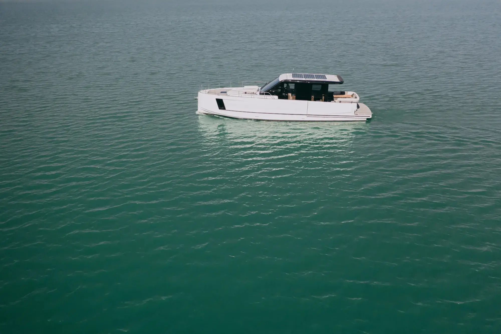 Die weiße Wia 520 HardTop in Fahrt, ihr dunkles Hardtop mit Dach-Solarmodulen über dem geschlossenen Salon und Teakdecks.