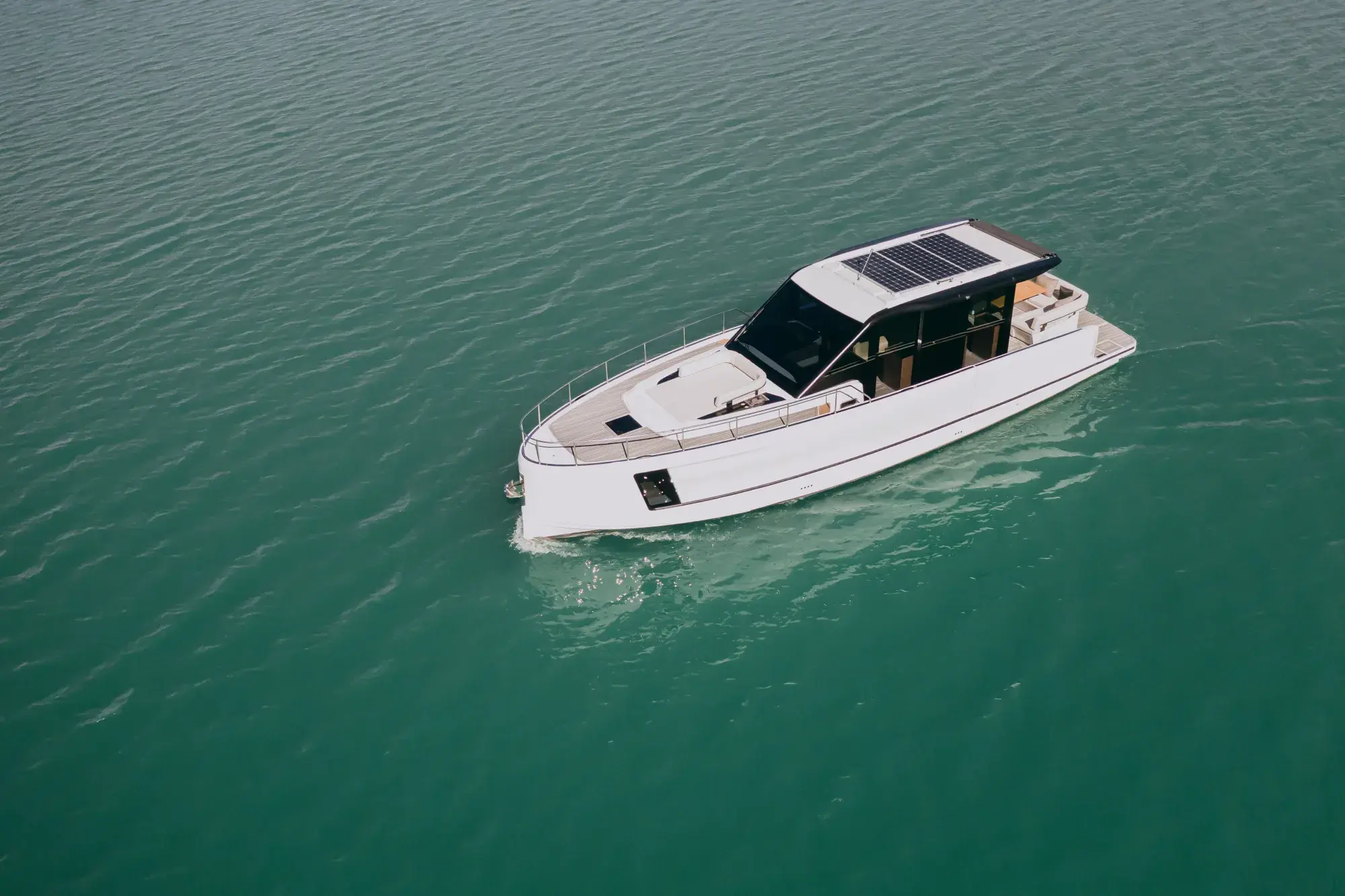 Die weiße Wia 520 HardTop in Fahrt, ihr dunkles Hardtop mit Dach-Solarmodulen über dem geschlossenen Salon und Teakdecks.