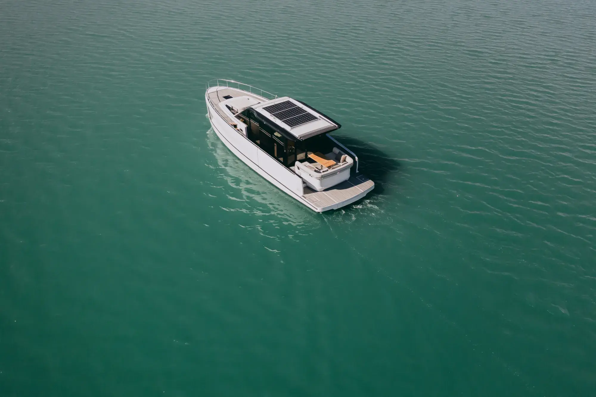 Die weiße Wia 520 HardTop in Fahrt, ihr dunkles Hardtop mit Dach-Solarmodulen über dem geschlossenen Salon und Teakdecks.