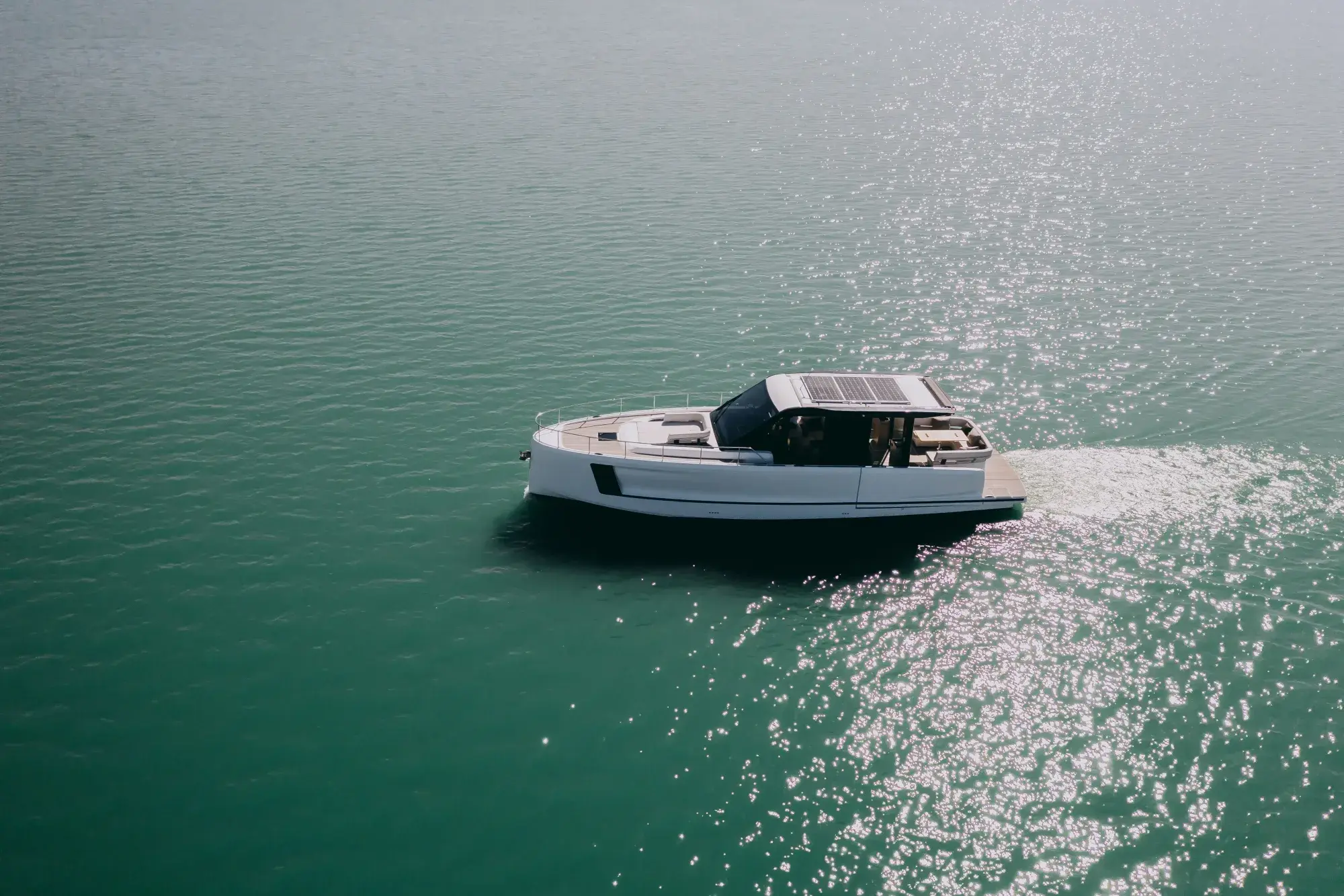 Die weiße Wia 520 HardTop in Fahrt, ihr dunkles Hardtop mit Dach-Solarmodulen über dem geschlossenen Salon und Teakdecks.