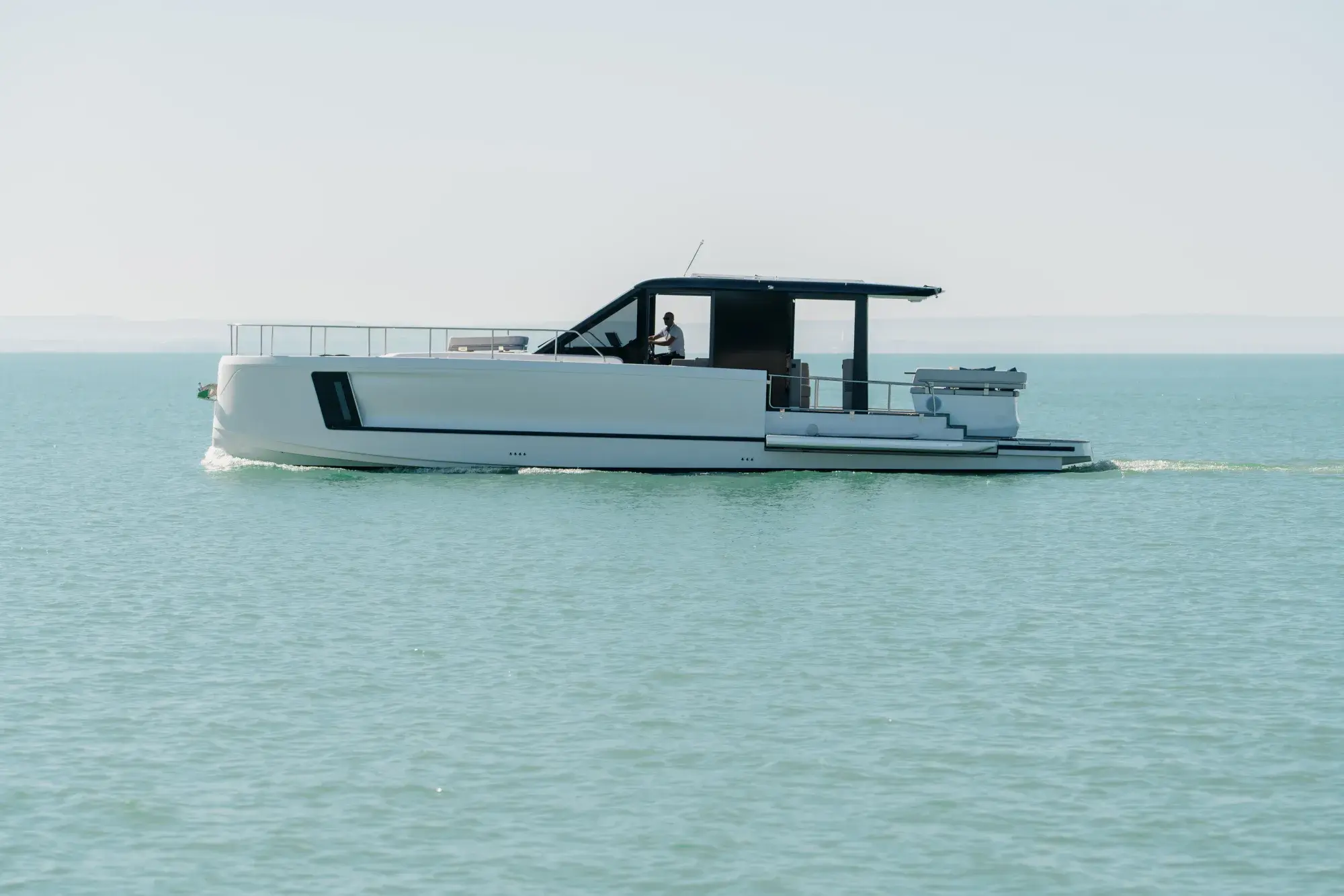 Die weiße Wia 520 HardTop in Fahrt, ihr dunkles Hardtop mit Dach-Solarmodulen über dem geschlossenen Salon und Teakdecks.