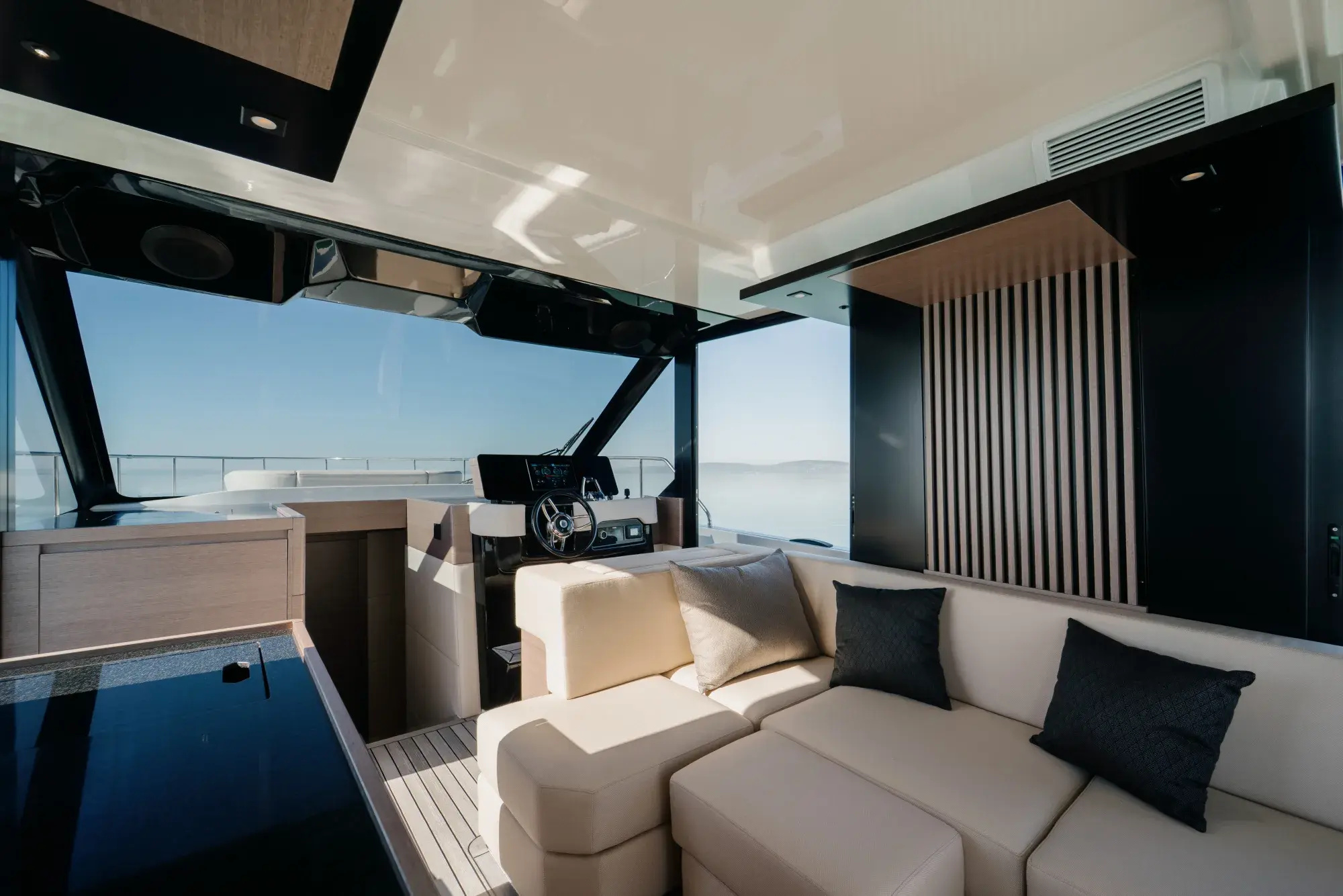 Le poste de barre du carré de la Wia 520 HardTop avec volant à rayons chromés, console tactile et sièges crème sous le hardtop.