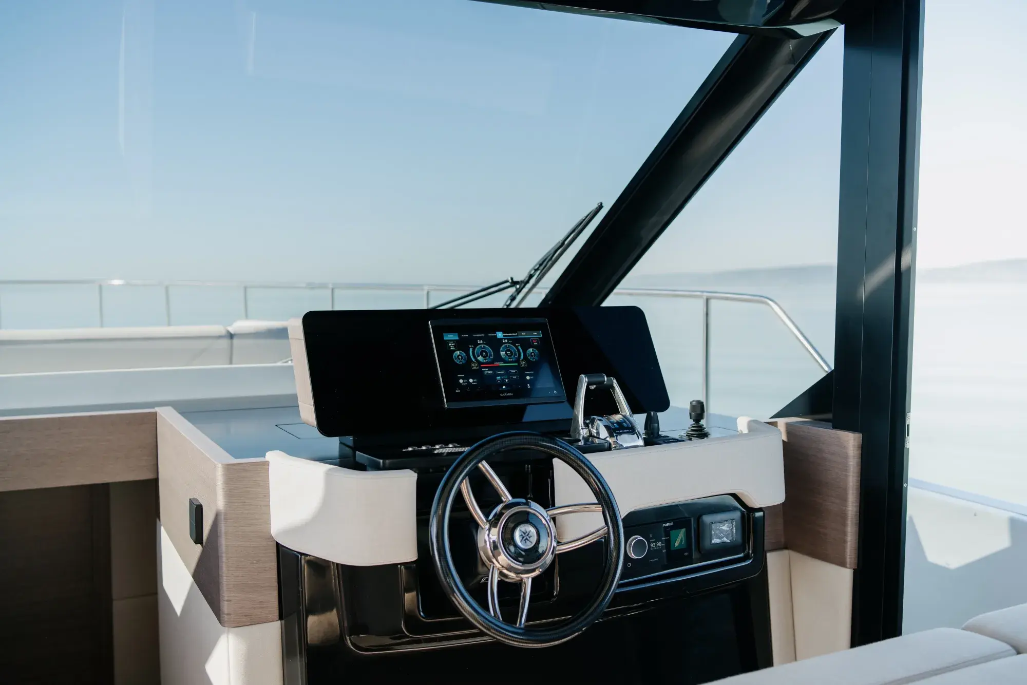 Der geschlossene Salon der Wia 520 HardTop: ein cremefarbenes L-Sofa, helle Eichenvertäfelung, eine Pantry mit dunkler Arbeitsplatte, ein Teakboden und der Steuerstand voraus, umgeben von Panoramafenstern.