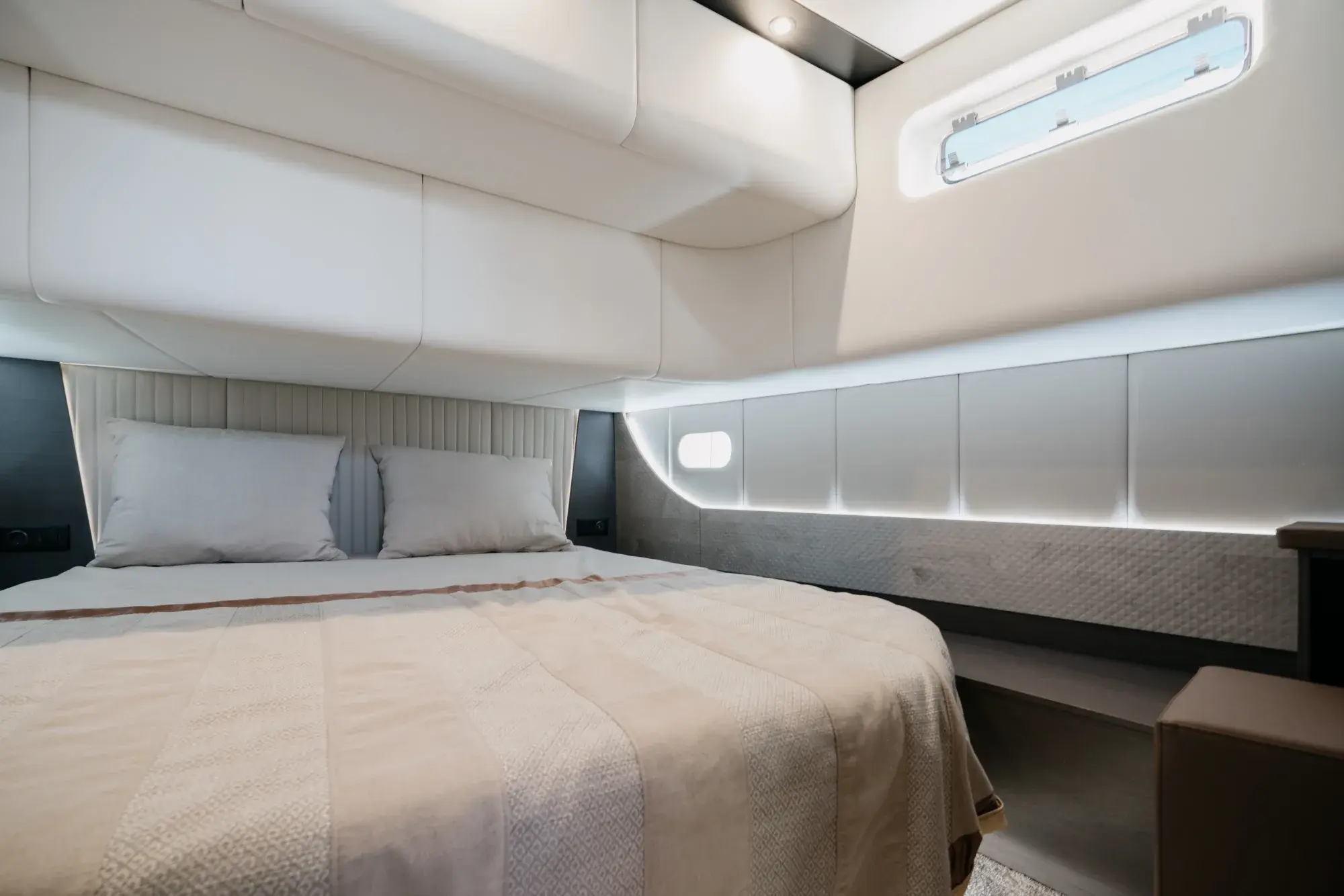 Eine Kabine der Wia 520 Open mit Doppelbett, cremefarbener Bettwäsche und heller Eichenvertäfelung.