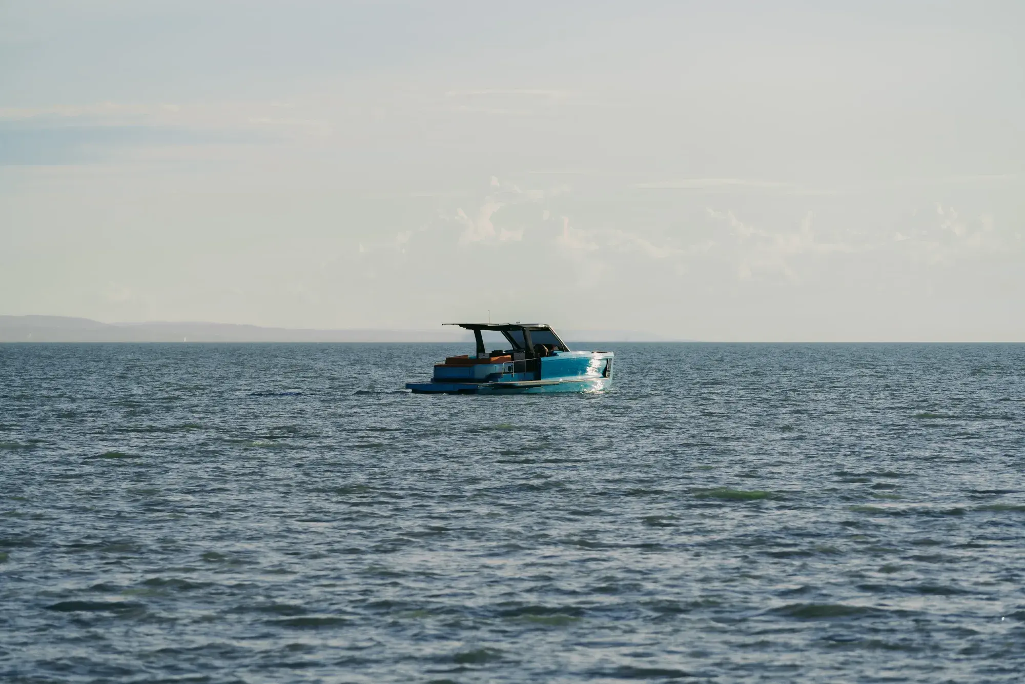 Die Wia 520 Open als Silhouette auf dem schimmernden, hinterleuchteten Wasser des Balaton, Hügel am Horizont.